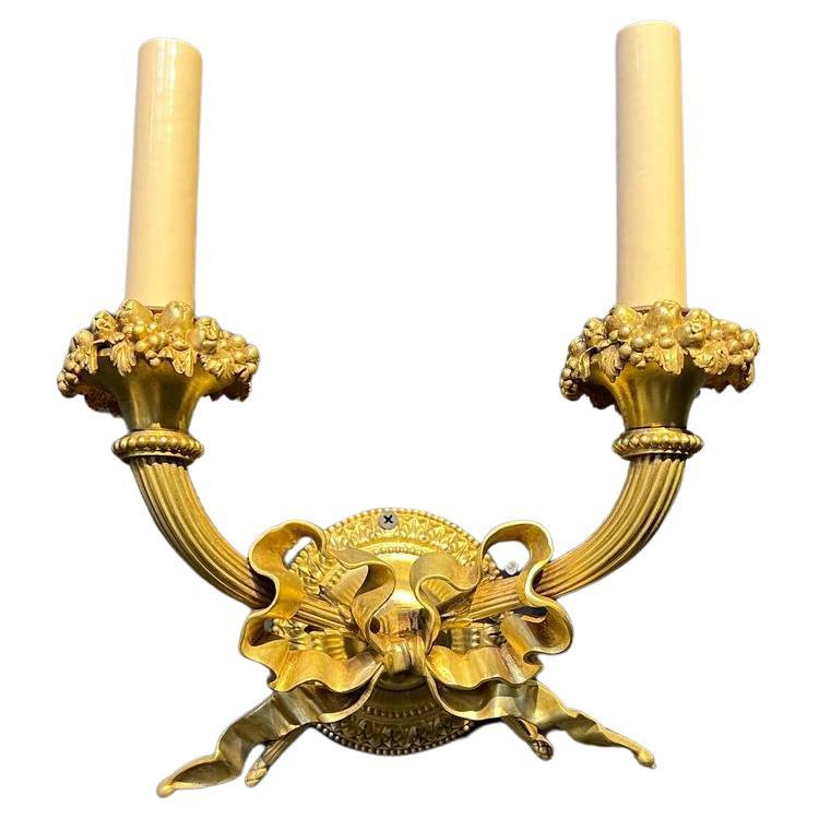 A pair of circa 1920's Caldwell gilt bronze double light sconces with ribbon design.