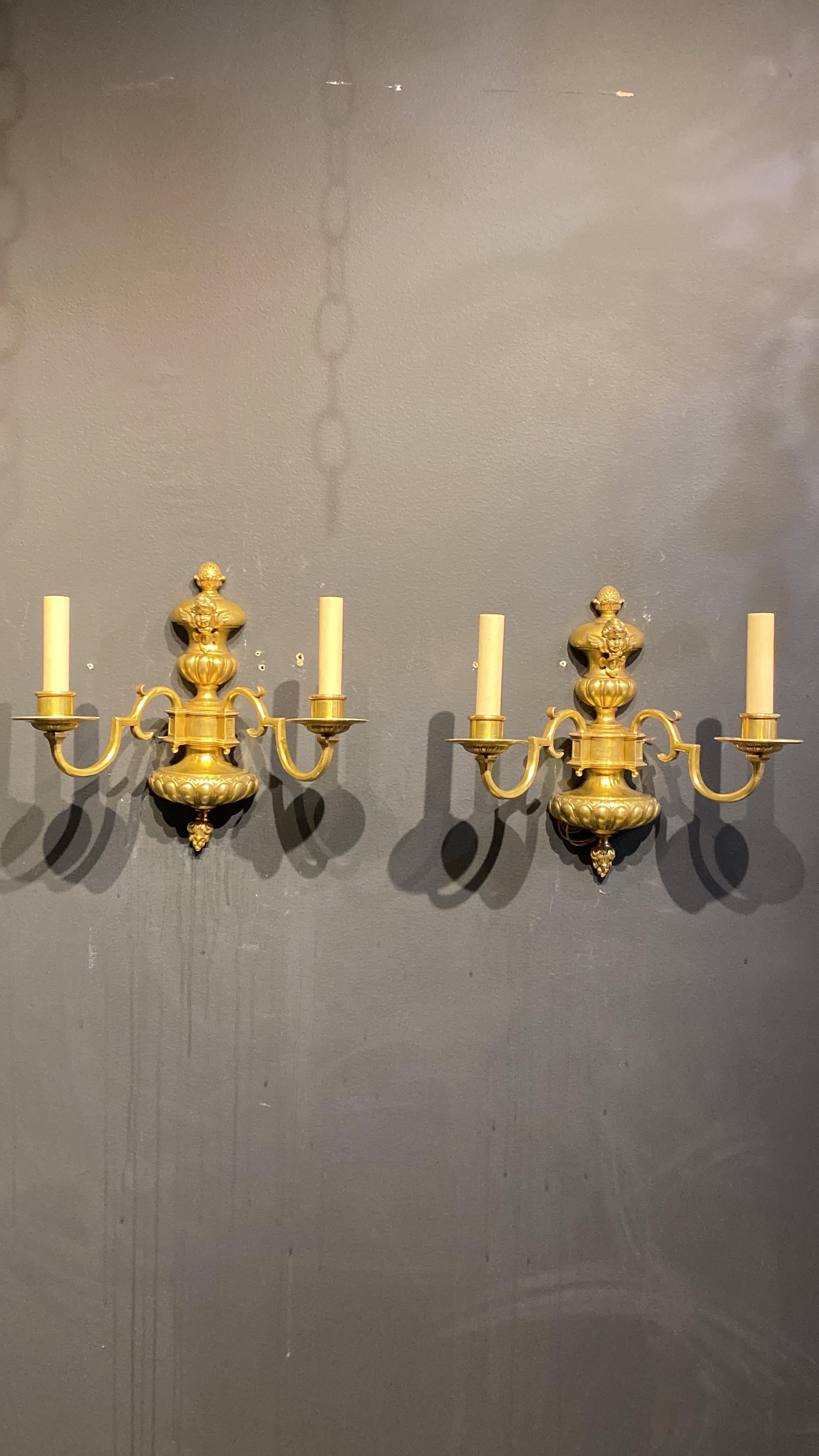 A pair of circa 1920's Caldwell double light sconces with cherub atop