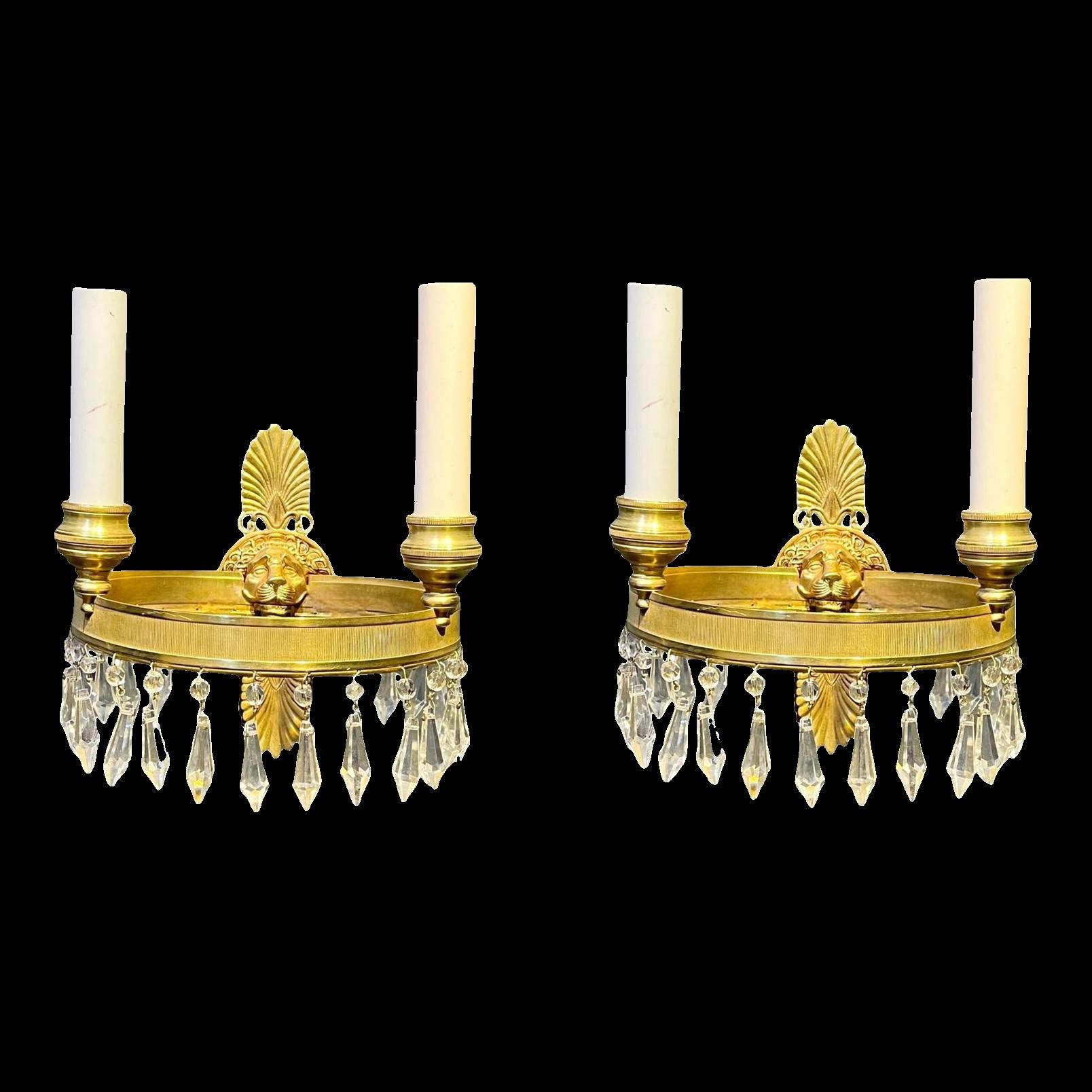 A pair of circa 1930's French gilt bronze sconces with lion's head and crystal hangings