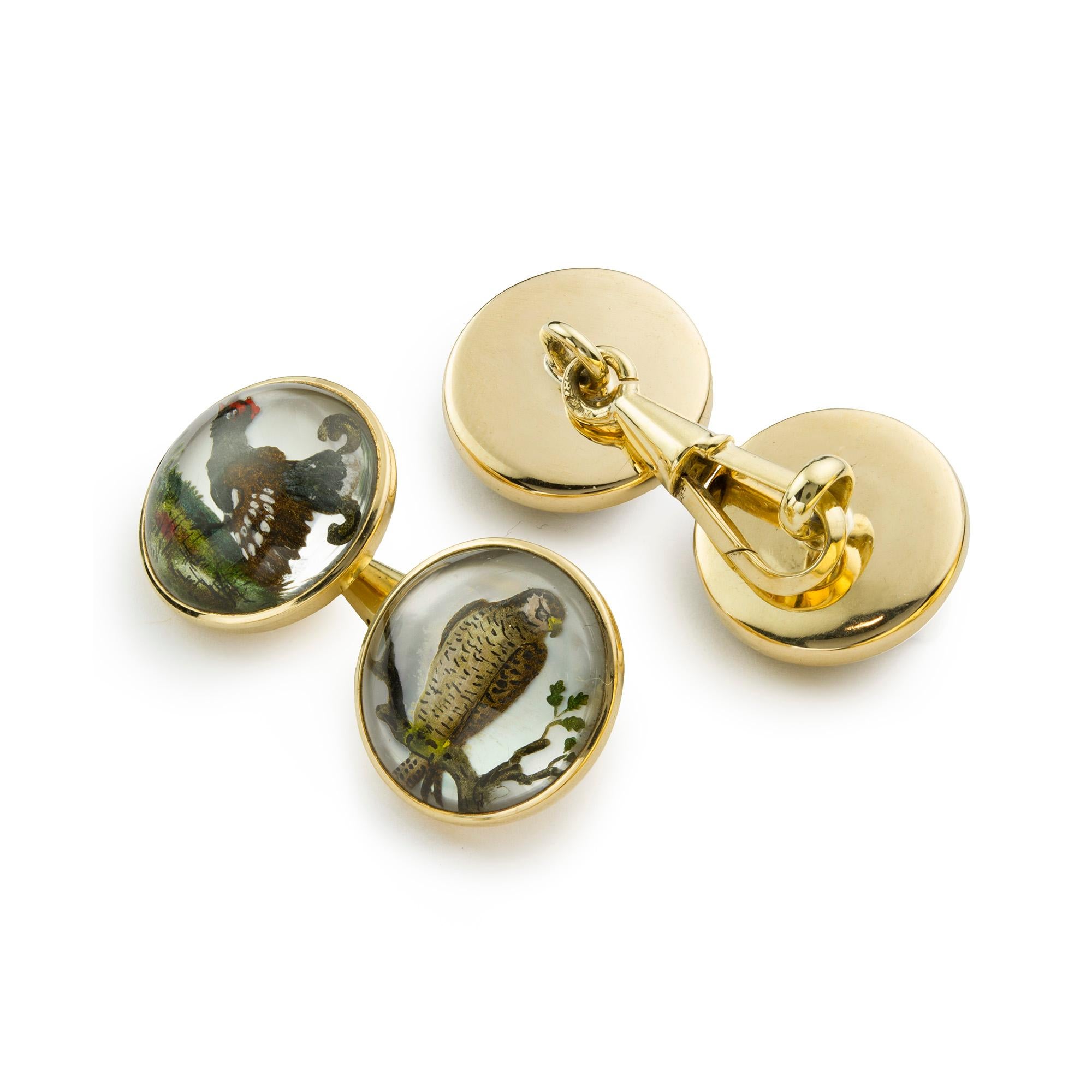 A pair of circular enamel and crystal cufflinks, depicting a peregrine falcon perching in a tree and a standing game bird, painted on mother of pearl, 1.4cm wide, all mounted in yellow gold stamped 750, continental, circa 1910, measures approx: 15 x