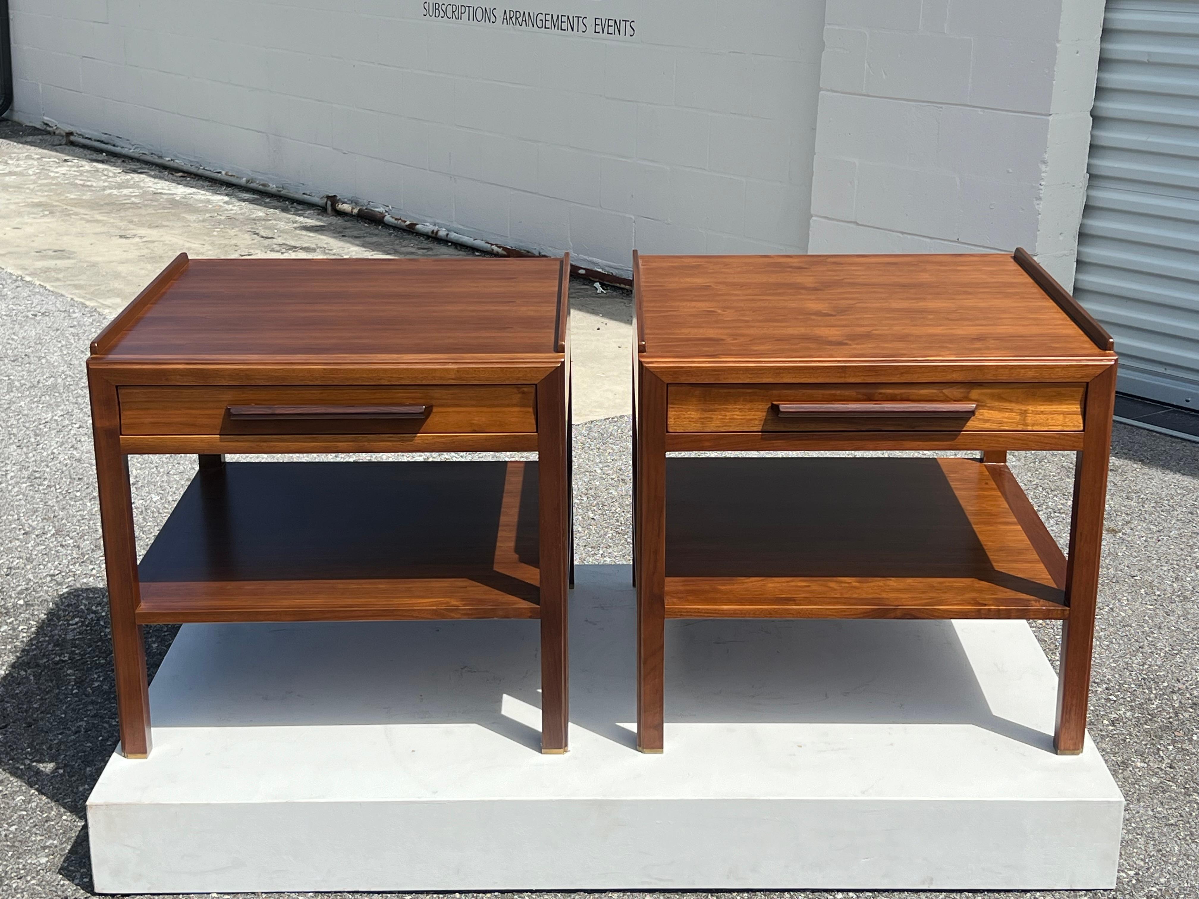 Paire de tables d'appoint ou de chevets conçues par Edward Wormley pour Dunbar et fabriquées à Berne, Indiana, vers les années 1960. Fabriqué en noyer avec des poignées en bois de rose. Le tiroir et l'étagère inférieure sont construits en queue