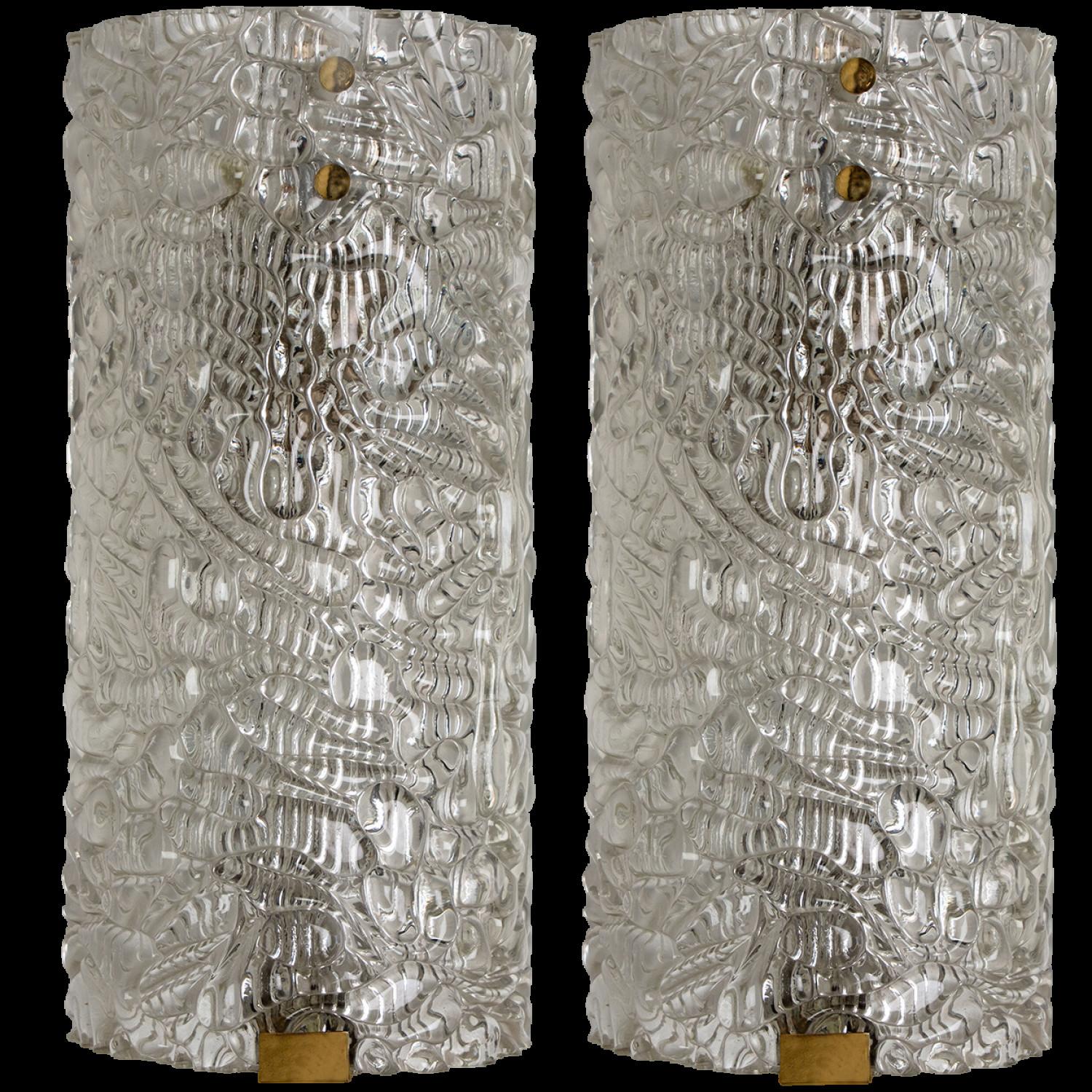Clean lines to complement all decors.  A pair of wonderful high-end wall light fixtures with brass detail and thick bubbled blown glass. Manufactured in the 1960s.
The glass of the light fixtures are made of clear textured glass giving the piece a