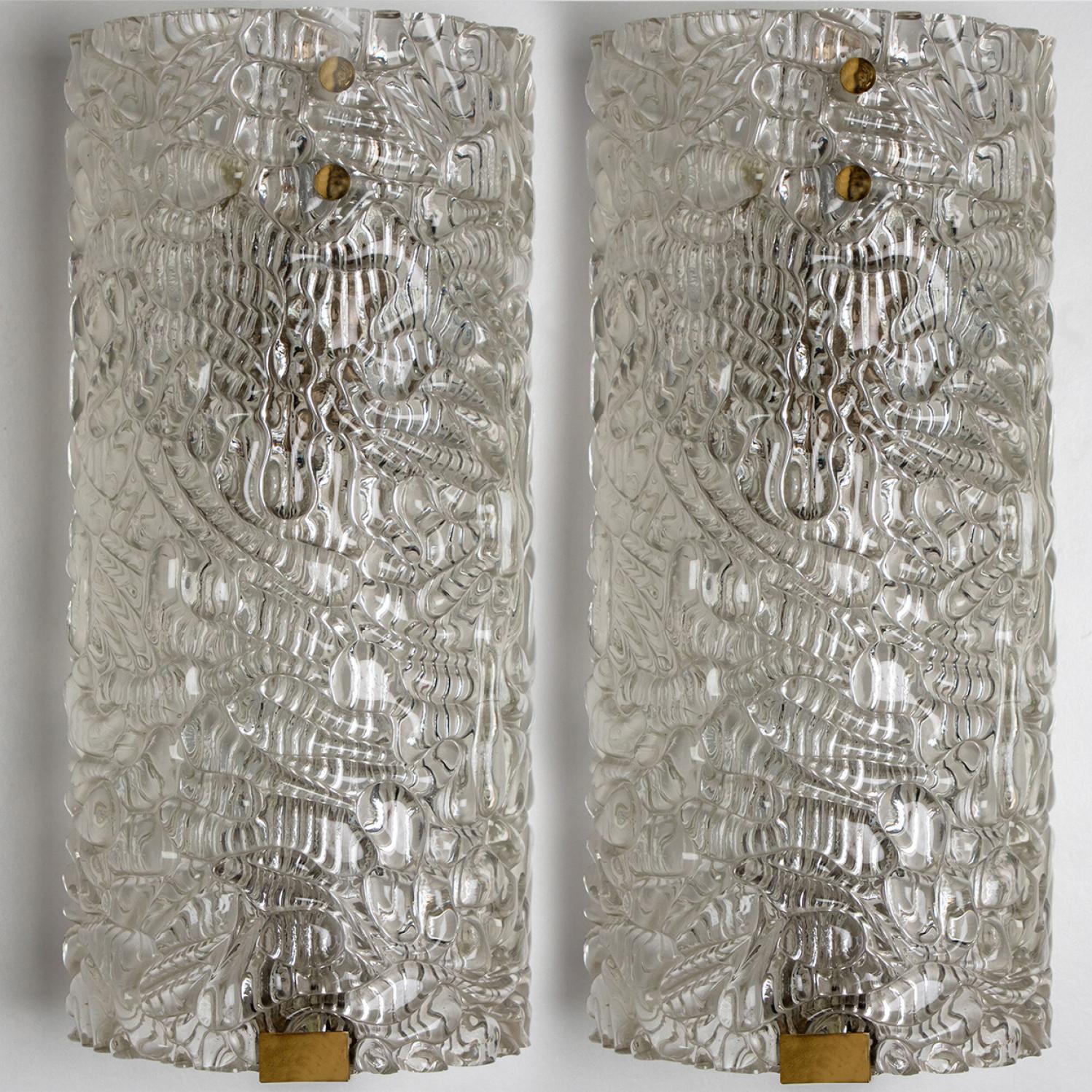 Clean lines to complement all decors.  A pair of wonderful high-end wall light fixtures with brass detail and thick bubbled blown glass. Manufactured in the 1960s.
The glass of the light fixtures are made of clear textured glass giving the piece a