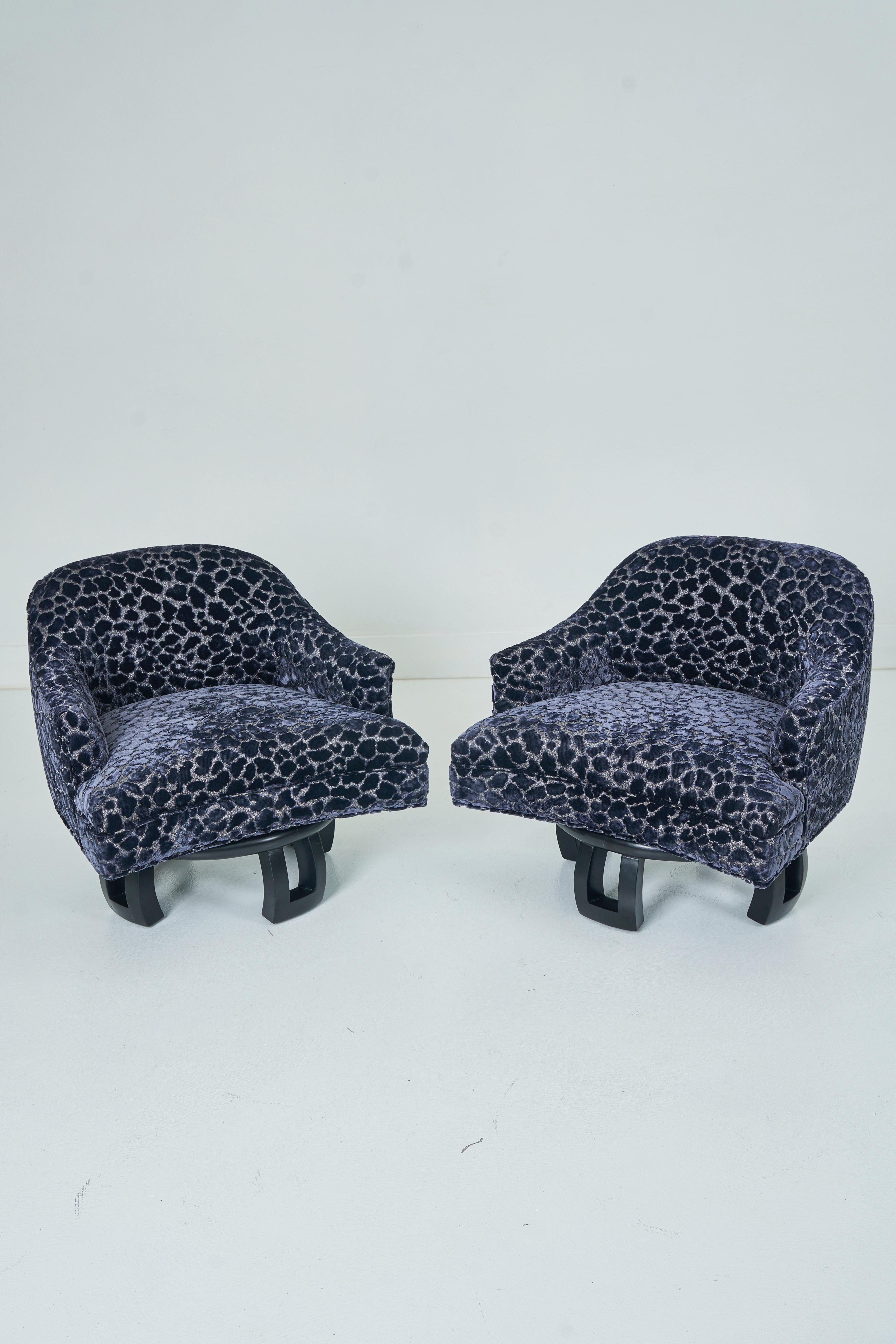 Offered here a pair of swiveling tub chairs, sitting on a stylized Chinoiserie base.  The bases are painted black.  The chairs have been newly upholstered in Romo/Zinc Ocelot - Midnight Blue Z516/03 .  These chairs are seldom seen on the market,