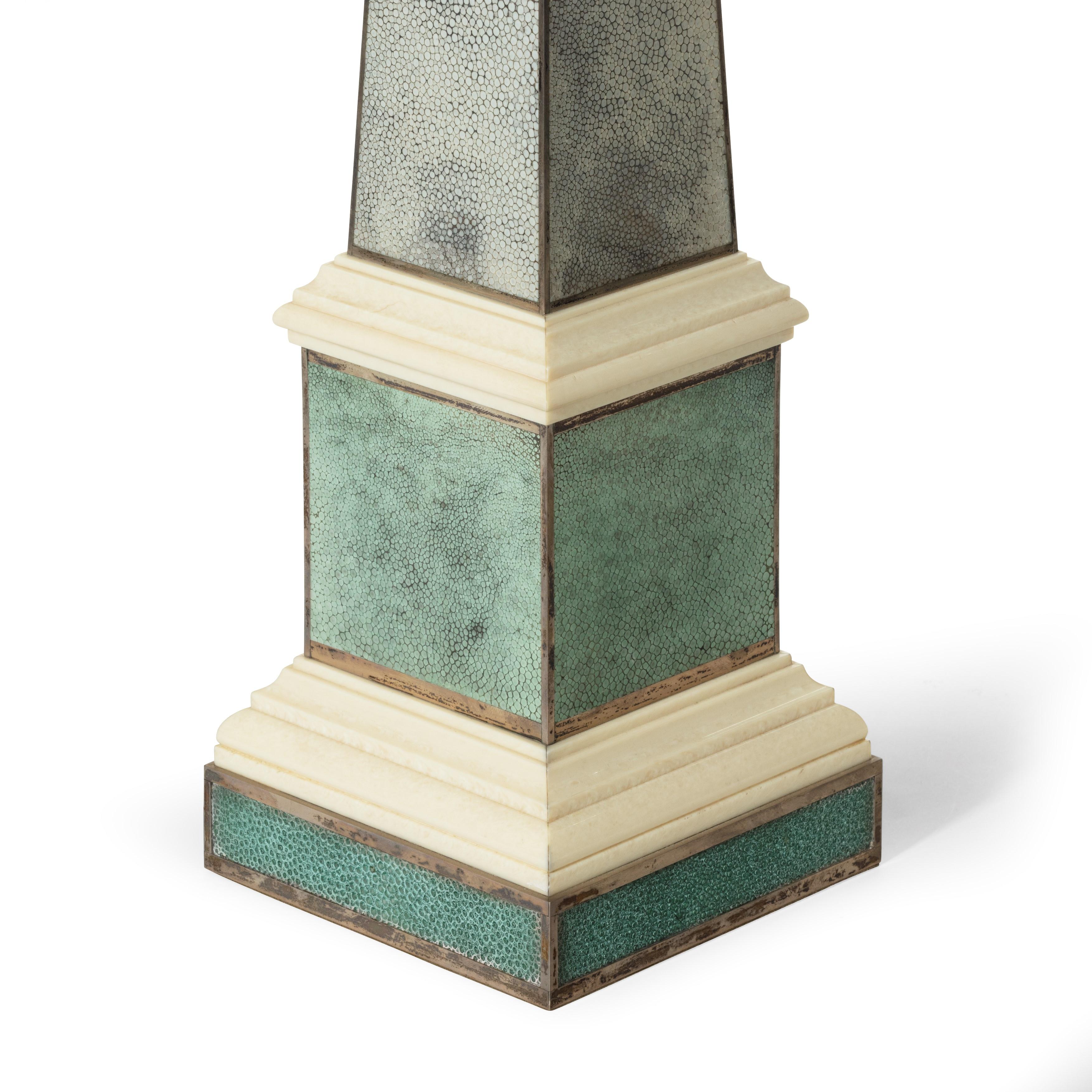 A pair of contemporary grey and aquamarine shagreen and obelisks, the square section pedestals with two stepped ivorine plinths, all with silver edging. 

English, circa 2010.
  