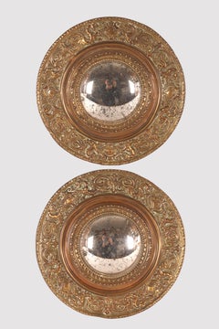 A pair of convex mirrors, brass stylized figures frame. Italy, 19th century.