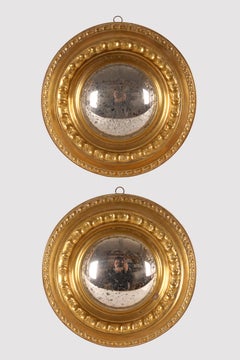 A pair of convex mirrors with embossed brass frames. Italy, late 19th century.