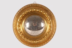 A convex mirror with embossed brass frames. Italy, mid 19th century.
