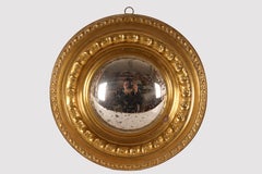 A convex mirror with embossed brass frames. Italy, mid 19th century.