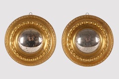 A pair of convex mirrors with smooth, embossed brass frames. Italy, circa 1890.
