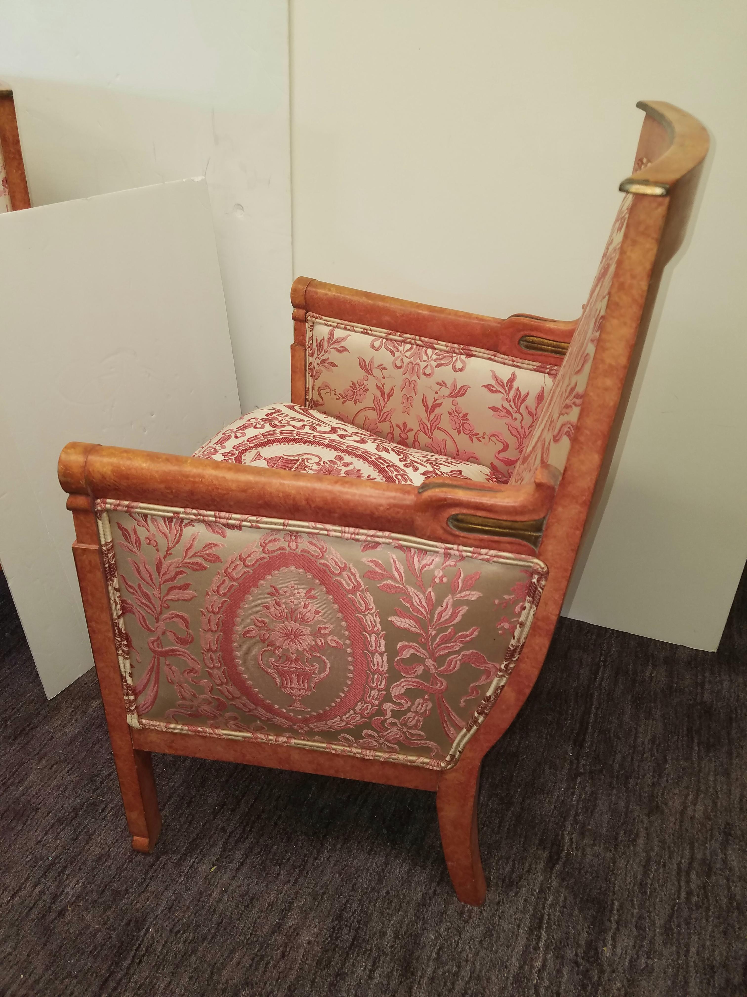 A pair of elegant 1920s Empire style armchairs with coral painted finish upholstered in ivory and rose woven silk. Down seat cushions. The painted frames with gilt highlights.
        