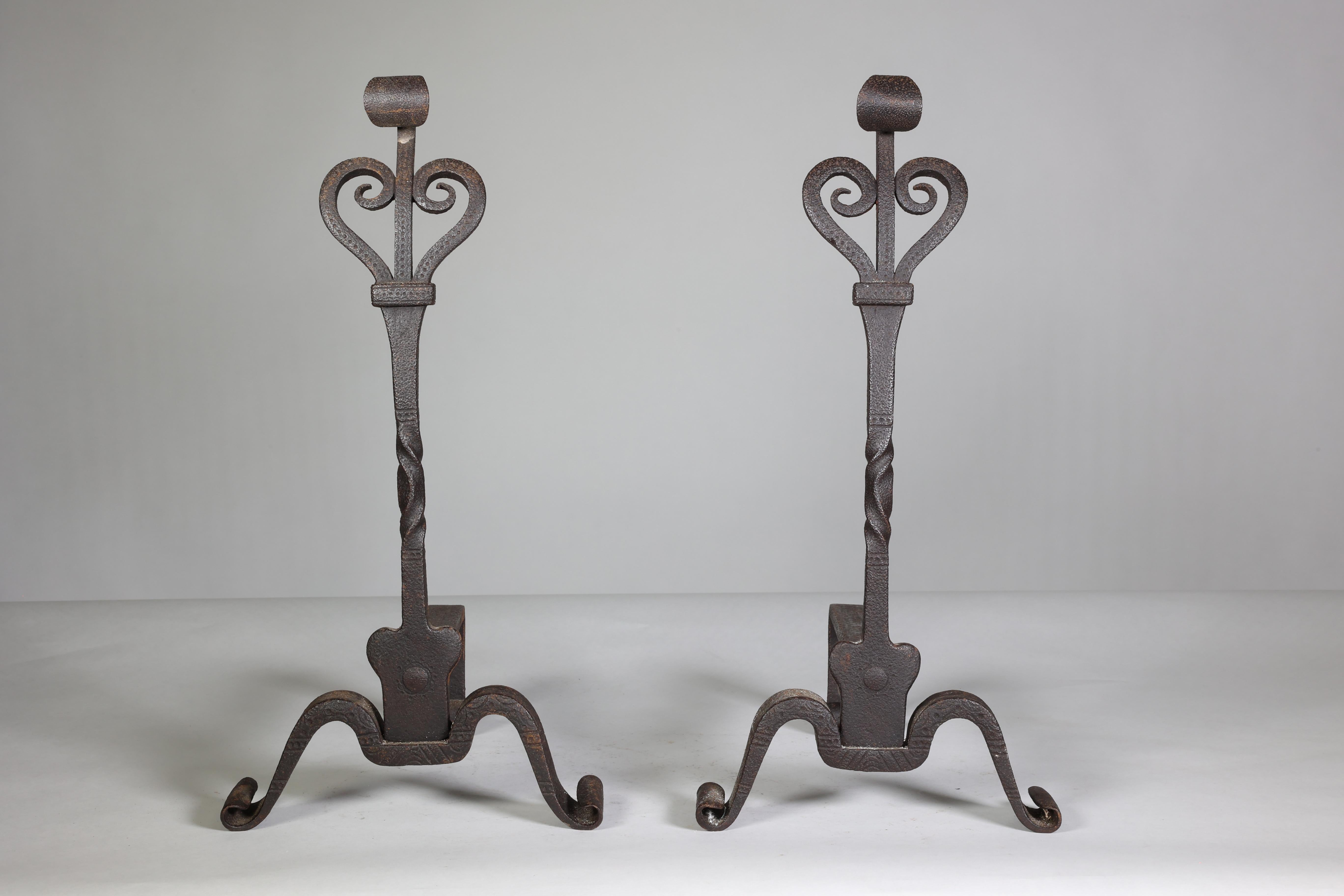 Thornton and Downer attributed. A pair of Arts and Crafts Cotswold School hand-made steel fire dogs with scroll tops and fine decorative chasing.
