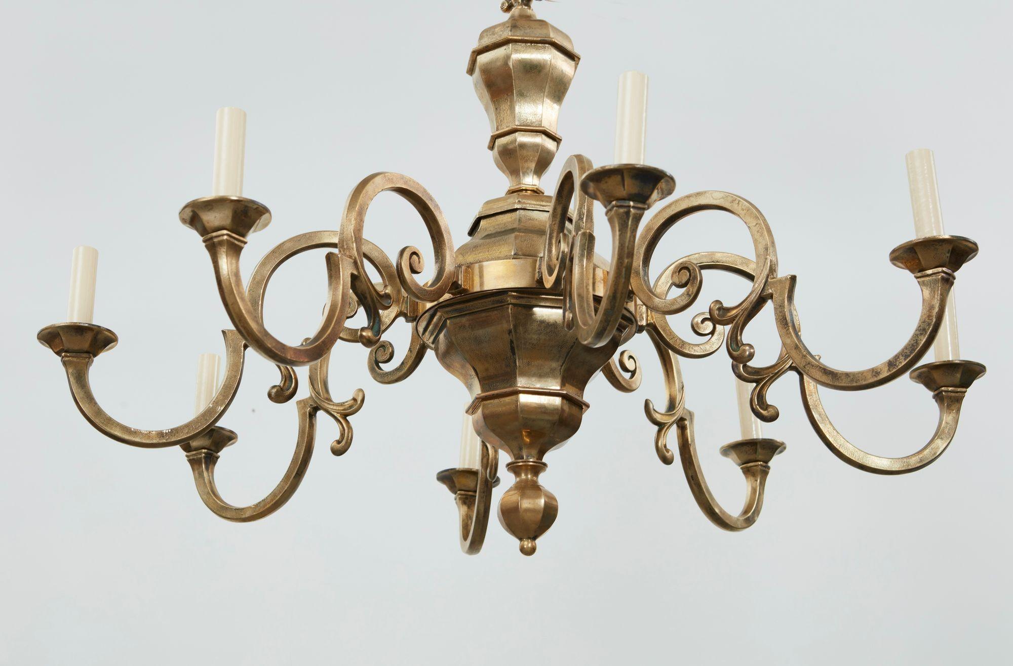 A rare pair of English country house brass chandeliers each with eight S-shaped faceted arms on elegant faceted bodies with conforming ceiling roses.  Good scale.  Now electrified.