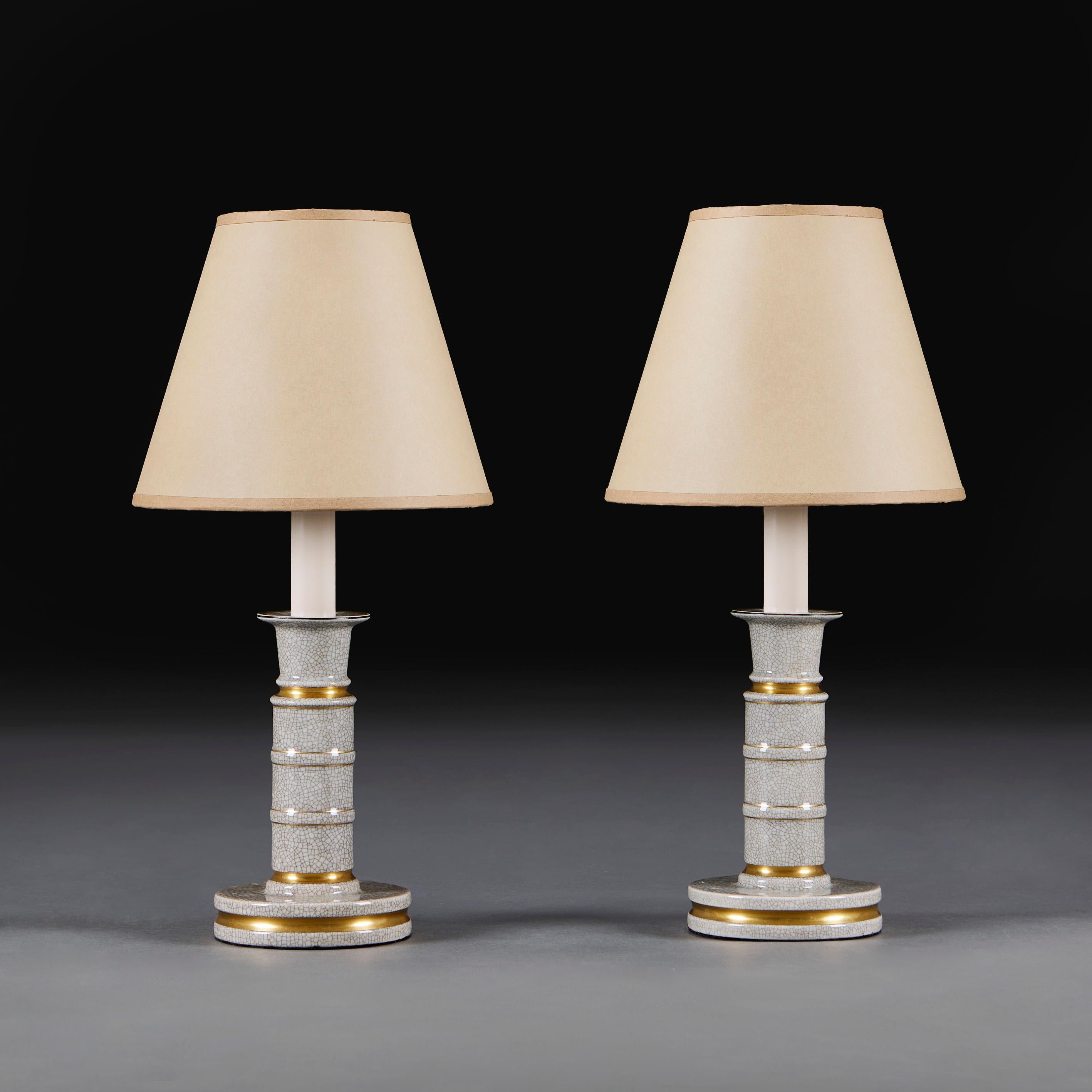 France, vers 1940
Paire de chandeliers du début du vingtième siècle en émail craquelé crème, avec des bandes dorées contrastées, aujourd'hui transformés en lampes.

Hauteur   25.00cm 
Hauteur avec abat-jour  42.00cm
Diamètre de la base 