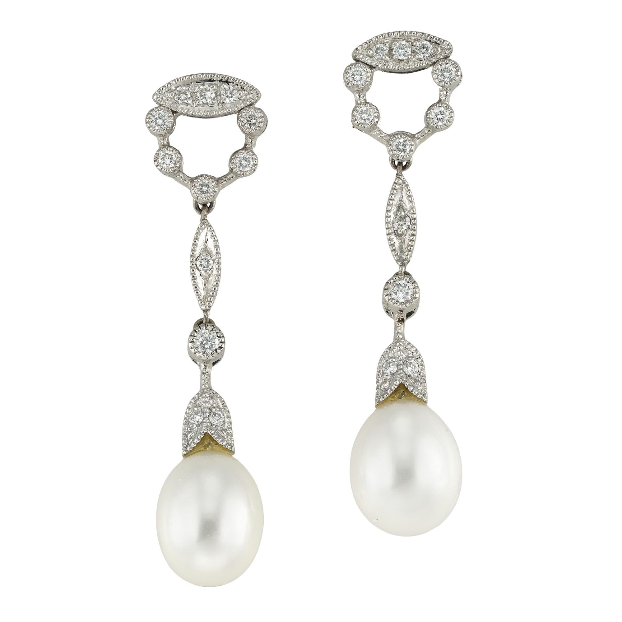 A pair of cultured pearl and diamond drop earrings, each earring consisting of a freshwater cultured pearl drop measuring approximately 9.5 x 7mm, attached to diamond-set foliate cap, surmounted by round and marquise shape diamond-set line,