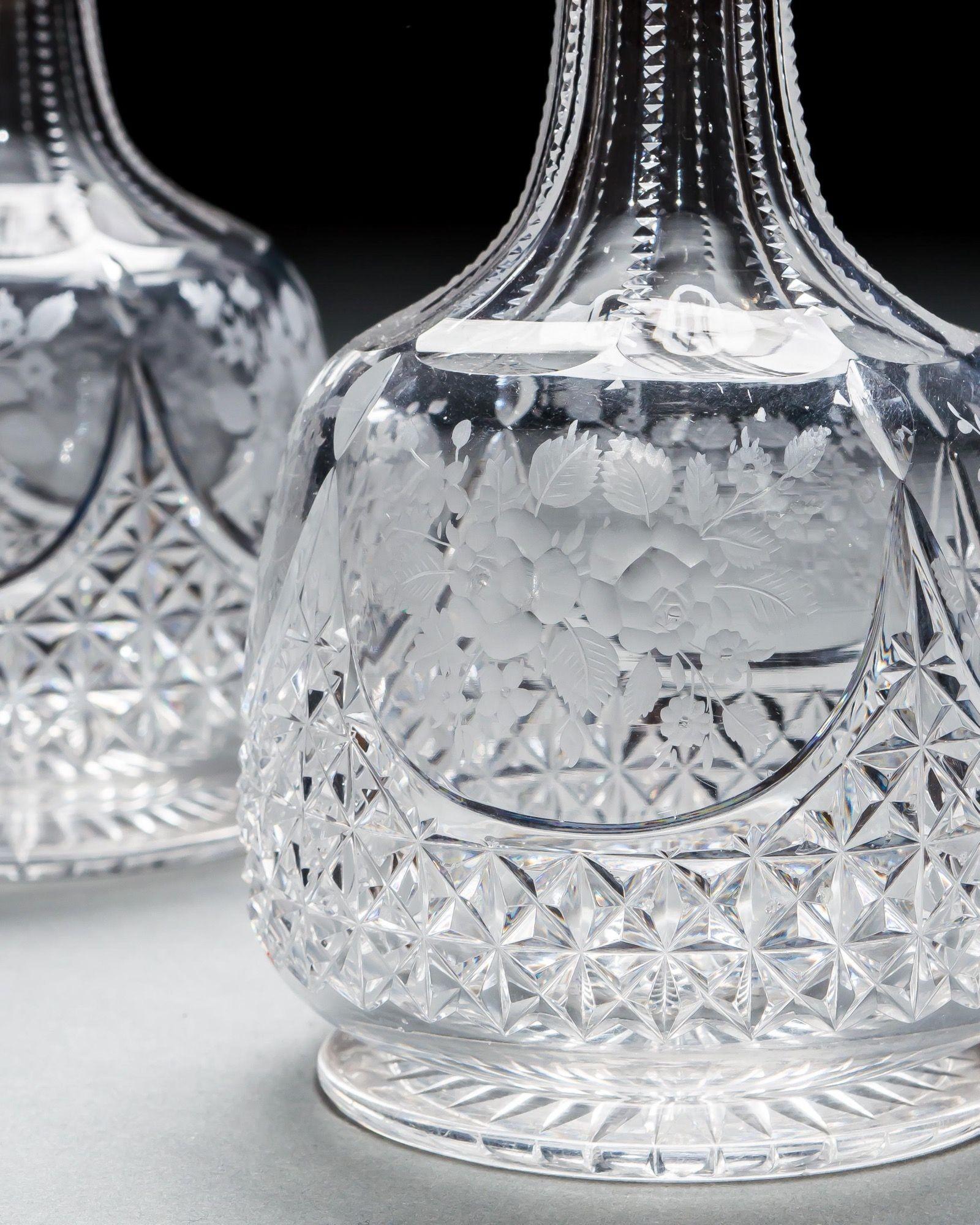 Une paire de carafes à eau victoriennes avec des corps en diamant taillé et des panneaux de fleurs gravés, avec des cols taillés en encoche.