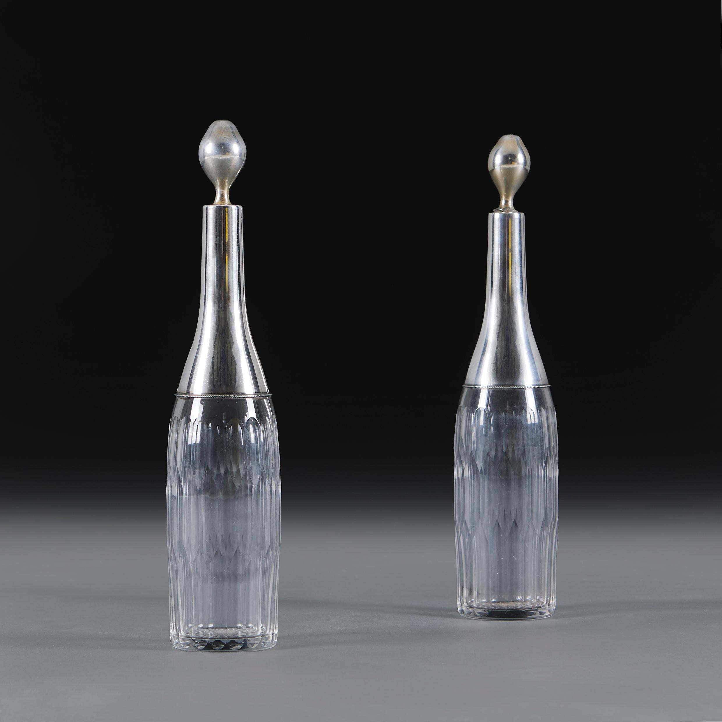 Pareja de decantadores de vino de vidrio tallado de finales del siglo XIX, uno para vino tinto y otro para vino blanco, con cuellos y tapones plateados. 

Altura    32.00cm
Diámetro   7.00cm