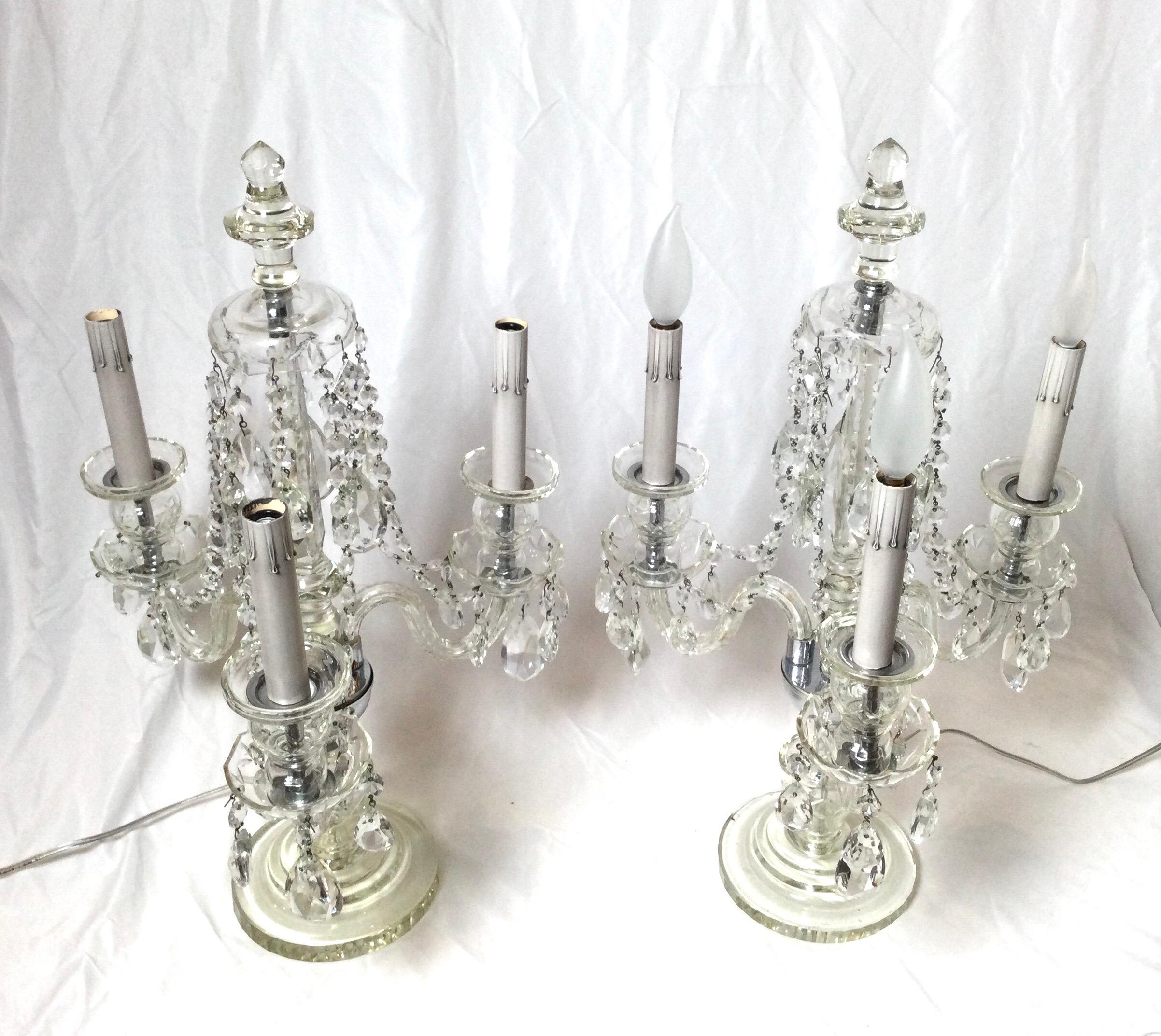 A pair of elegant cut glass and crystal three light girandole lamps. The center spire with three glass arms with light, accented with beaded chains and crystal drops.