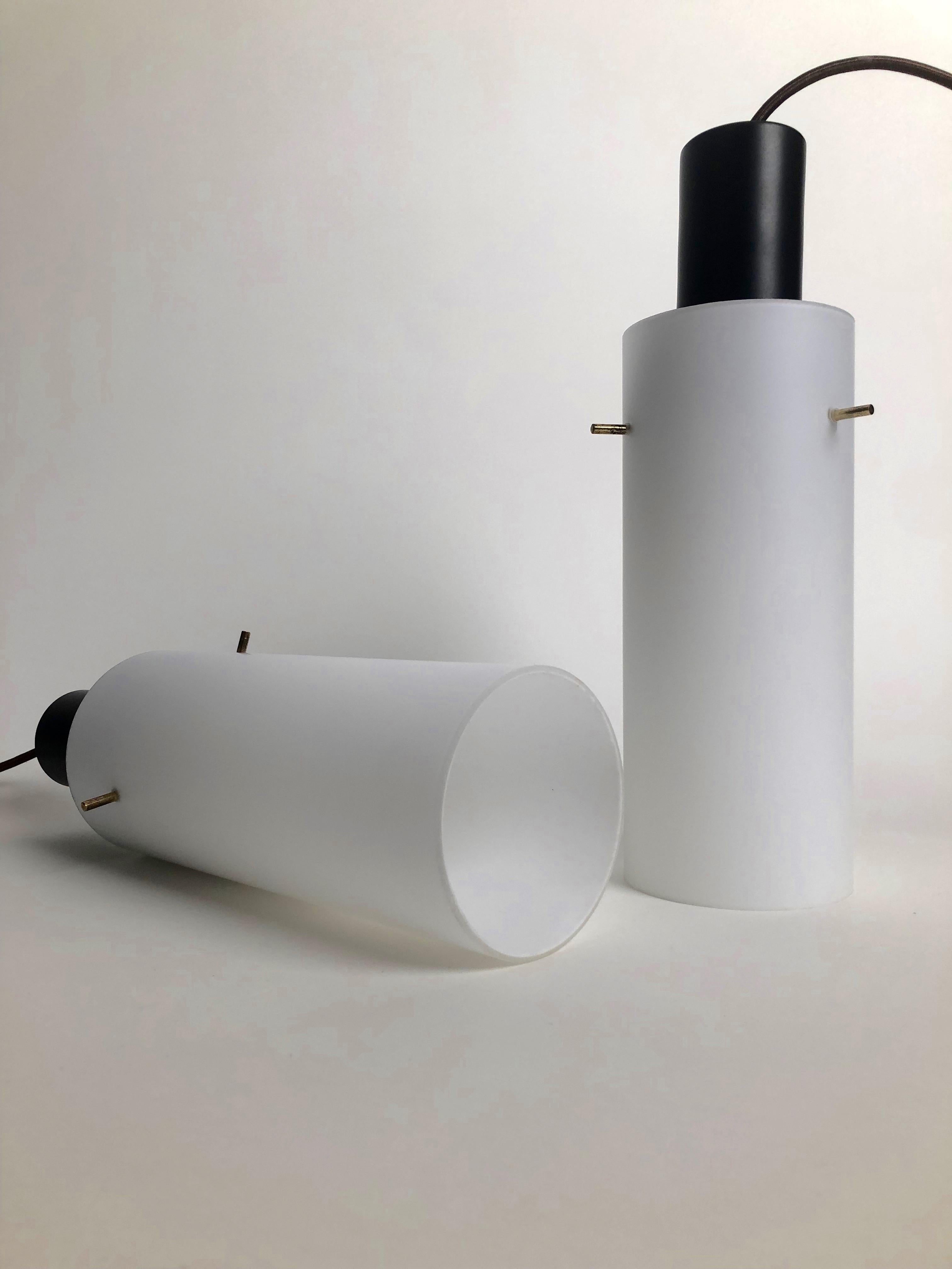 Una coppia di lampade a sospensione di forma cilindrica, appese al soffitto con un cavo rivestito in tessuto. Questi cilindri di vetro sono sospesi su tre perni di ottone, una soluzione elegante che fa molto Vienese. Questo set può essere utilizzato