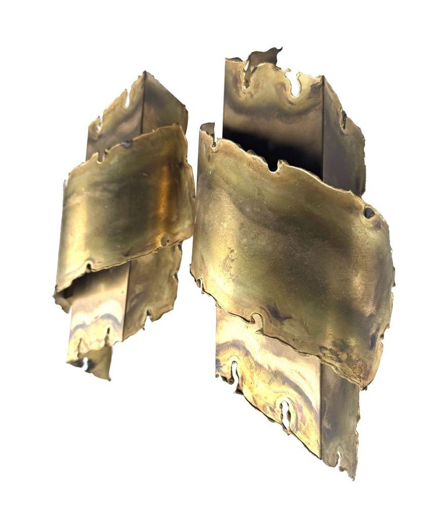 A pair of Danish 1960s torch cut brass, brutalist wall sconces by Holm Sorensen. Each with a single fitting mounted on enamel wall plate, re wired with new brass fittings and PAT tested
