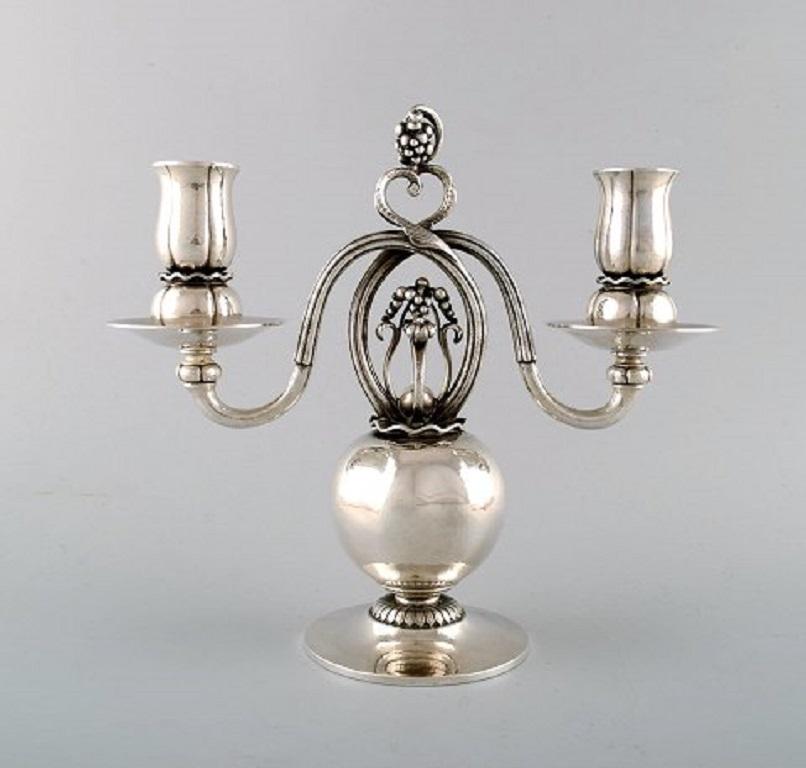 A pair of Danish silver two-light candelabra, designed by Georg Jensen.
Mark of GEORG JENSEN, COPENHAGEN.
Pomegranate pattern, each set on a circular base, rising to a stem formed as a pomegranate supporting the reeded entwined branches with a