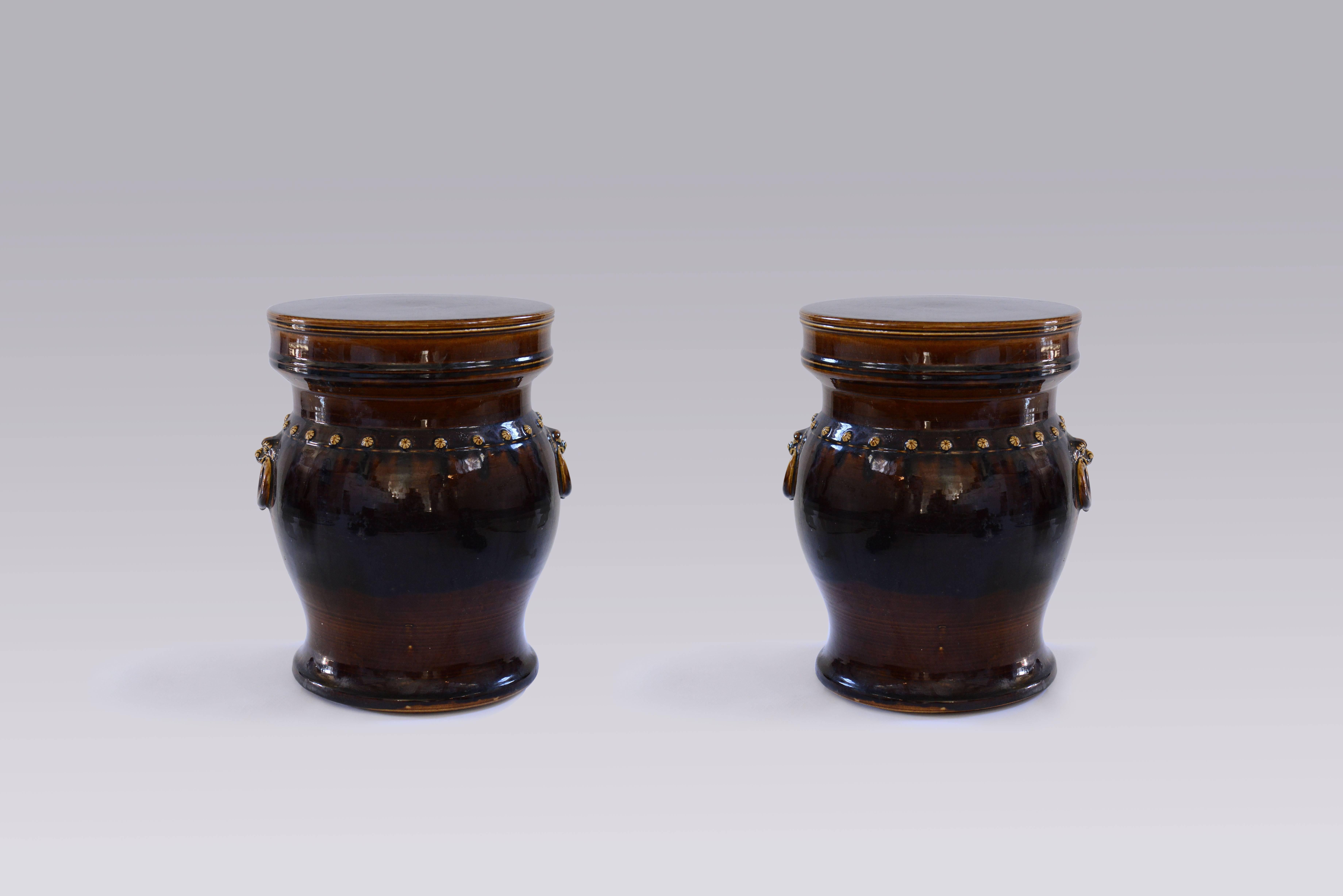 A pair of elegant dark glazed ceramic stools with handles.

