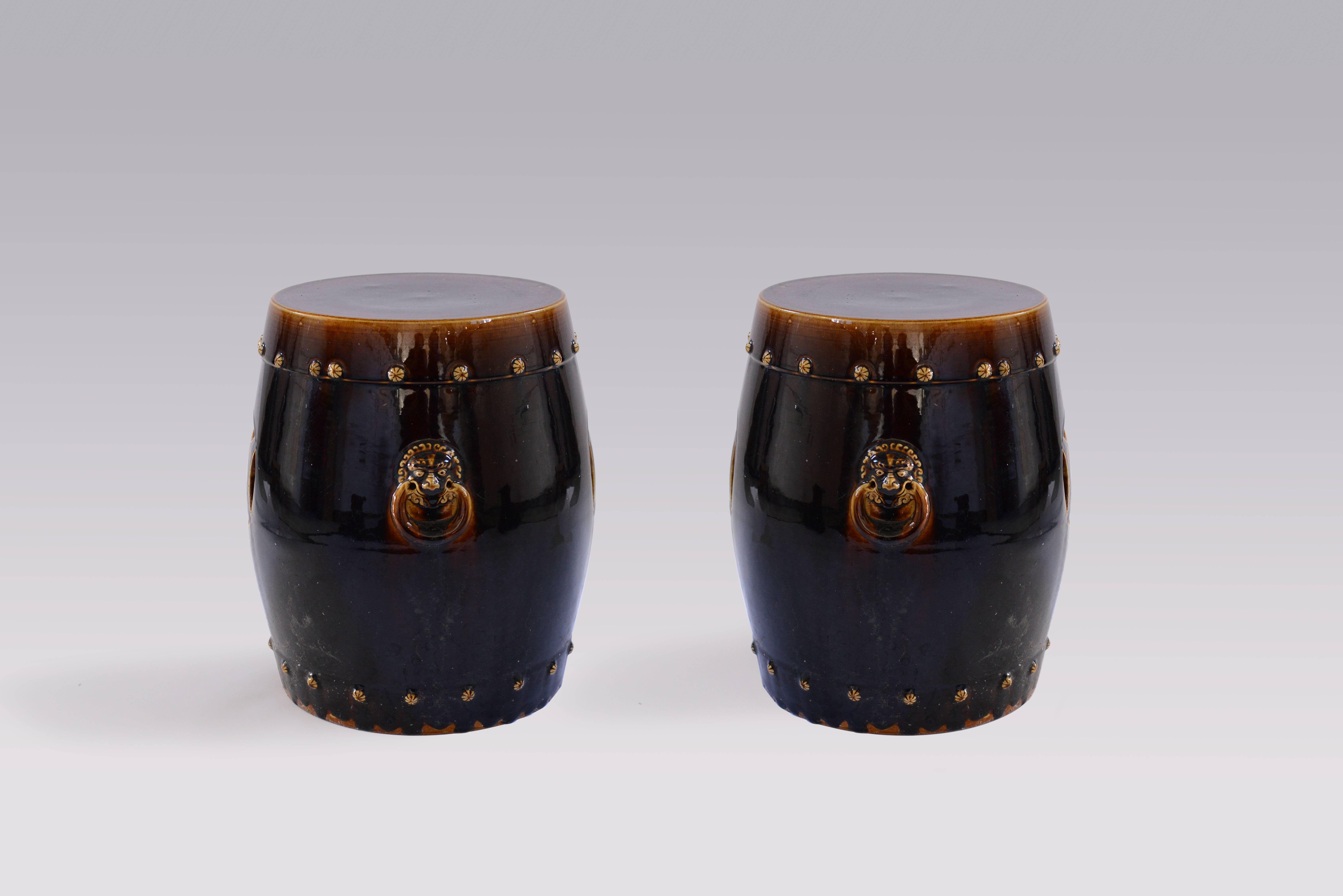 A pair of elegant dark glazed ceramic stools with handles.

