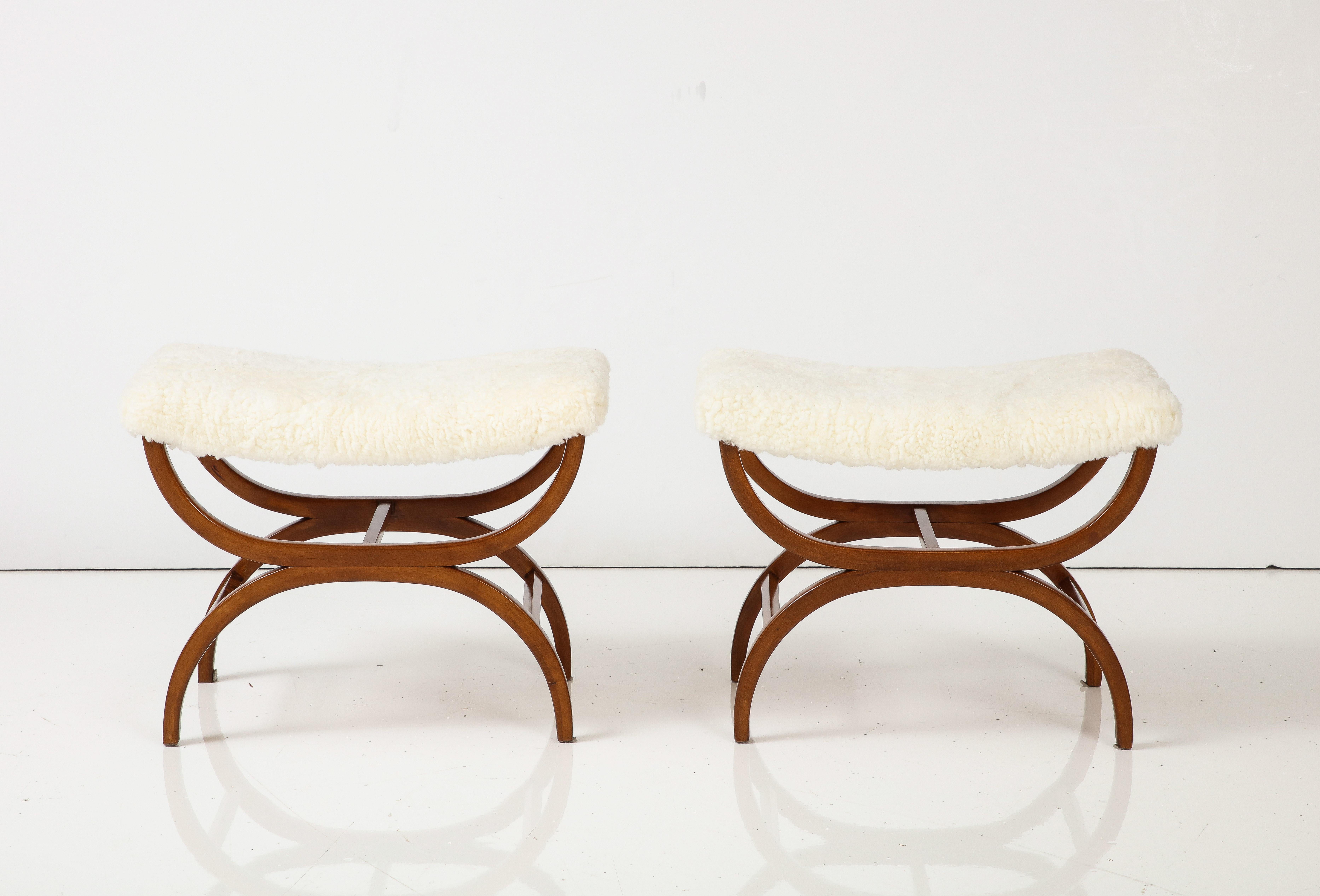 A pair of Swedish Modern mahogany stools, designed by David Rosen, circa 1940-50, of Curule form with a concave sheepskin seat.