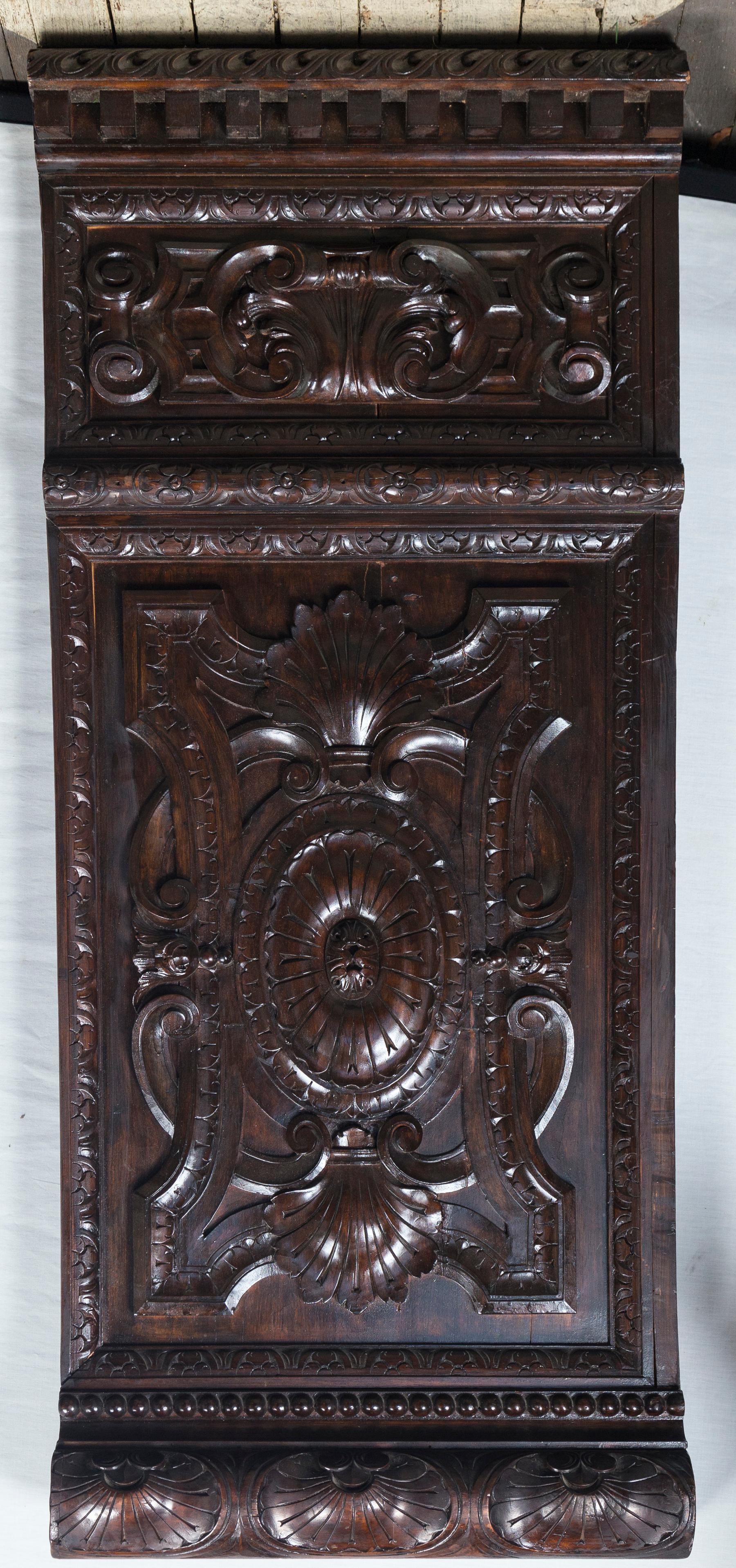 These panels are probably of mahogany. Carved fluted top edge. Dental molding below. Below is an inset panel showing a shell, within a carved frame. And C scrolls. Below that is carved molding which sits above another inset panel, decorated with