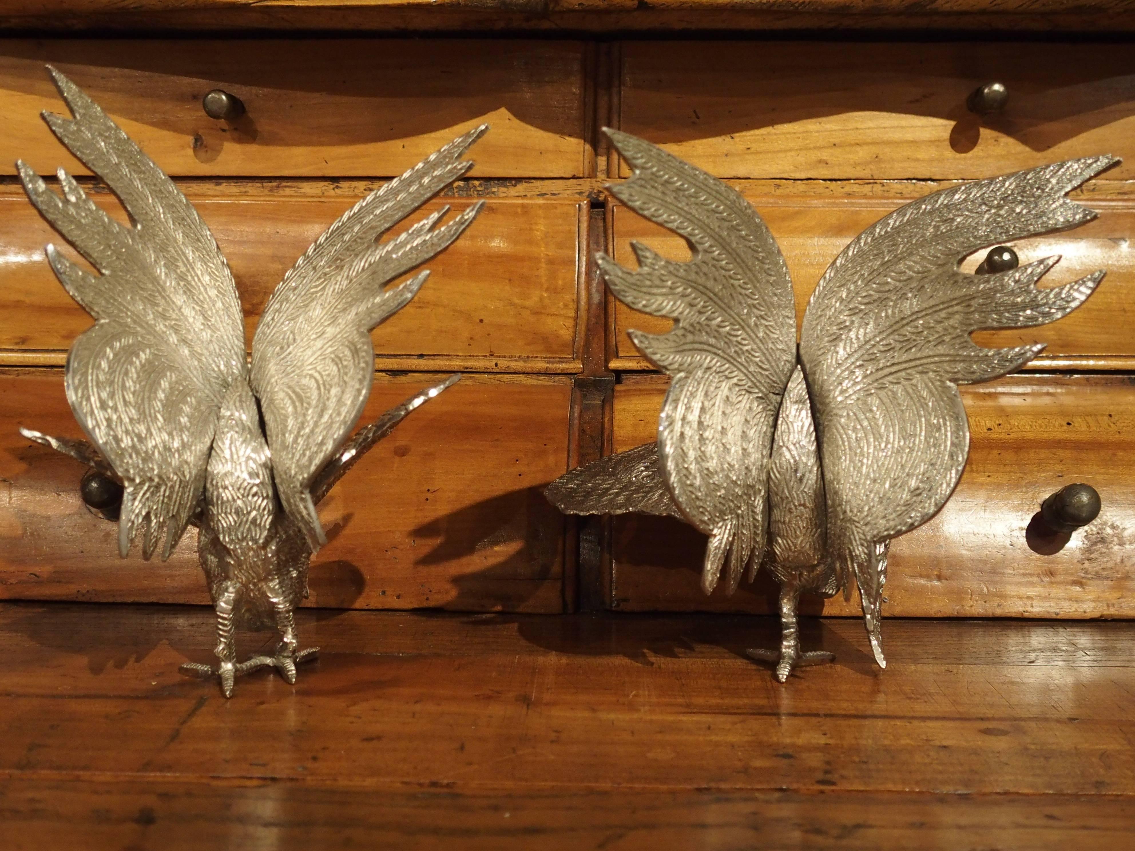 This stunning pair of decorative silvered roosters is from France and dates to sometime in the 20th century. They are in combative positions, perhaps posing for an all-out battle. The position of the wings, heads and bodies show fantastic movement,