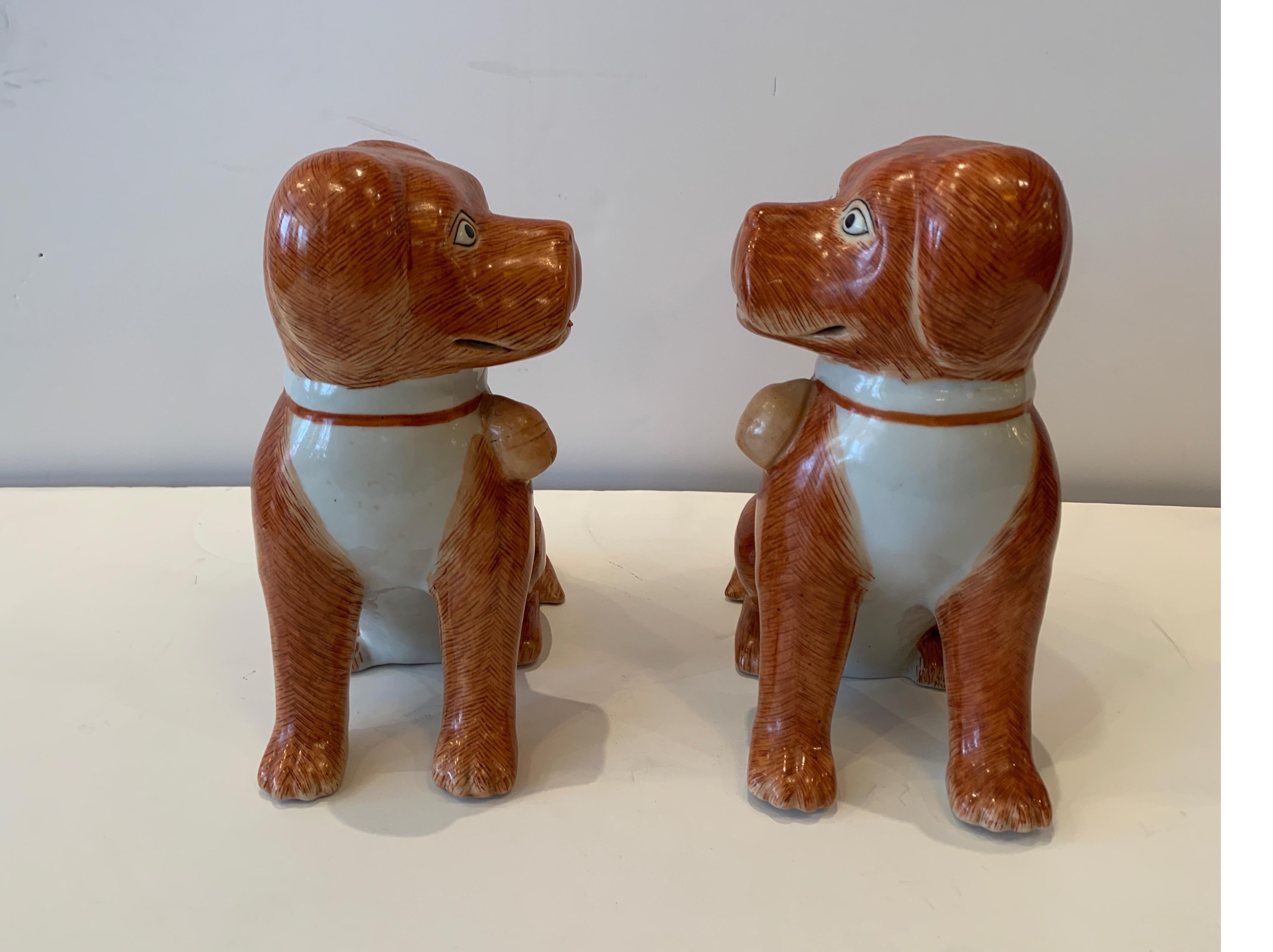 A pair of red painted Chinese porcelain dogs. The original pair one left facing the other right facing in an iron red pallet, 20th century.