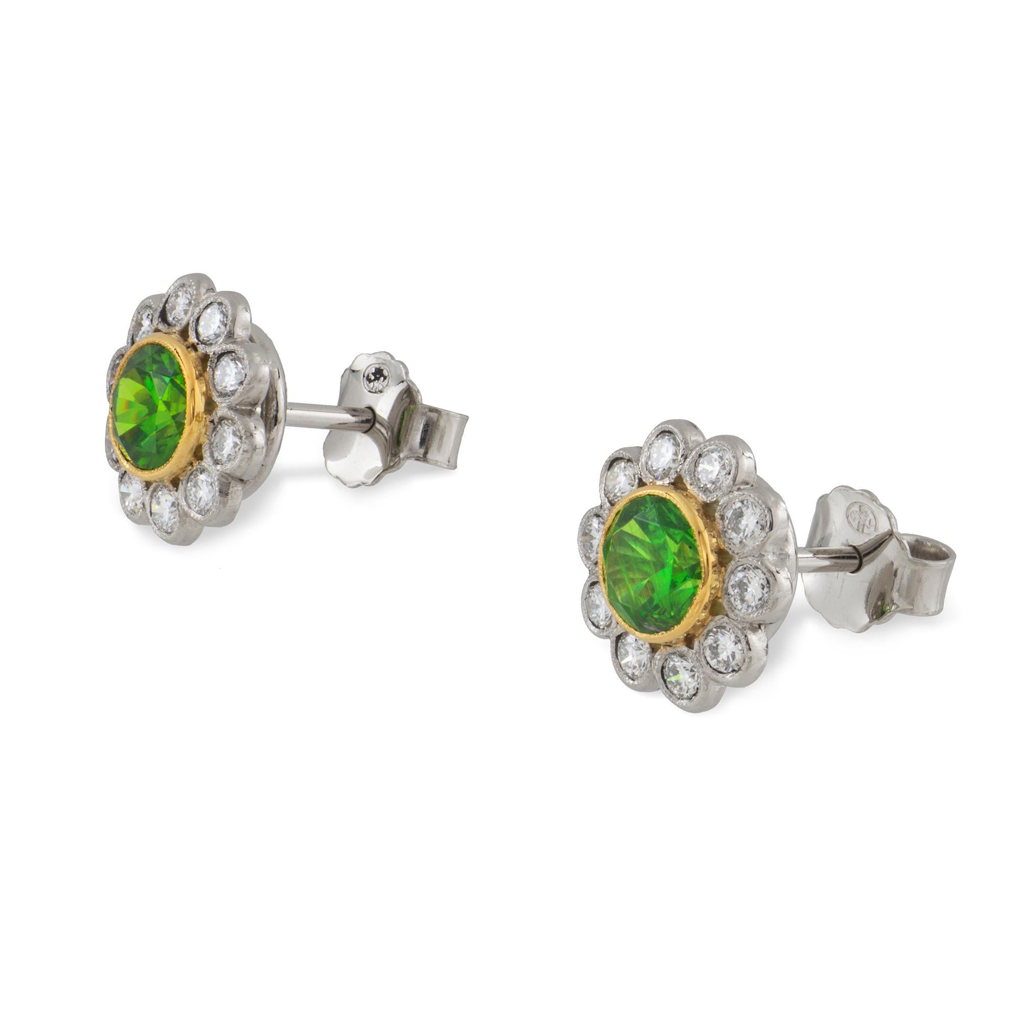 A pair of demantoid garnet and diamond cluster earrings, each demantoid millegrain-set to the centre of a round brilliant-cut diamond-set cluster, the demantoids have a total weight 1.48 carats and the diamonds weighing a total of 0.55 carats, all