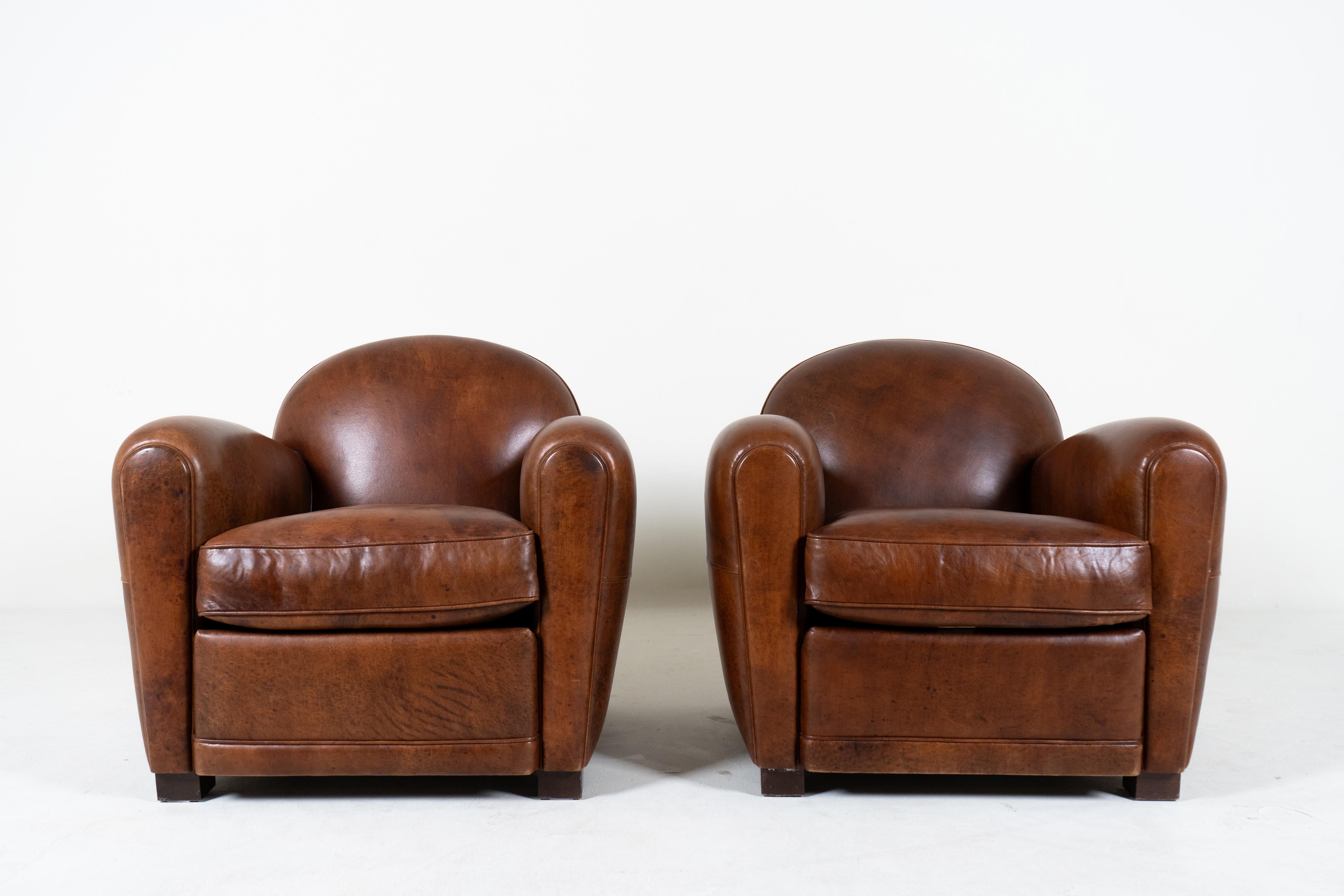 This pair of contemporary French Art Deco club chairs are a rare find. With a design dating to the Art Moderne movement from the 1920s-1940s, these chairs define an era of Parisian style. The striking nut-brown color has a beautiful softness and