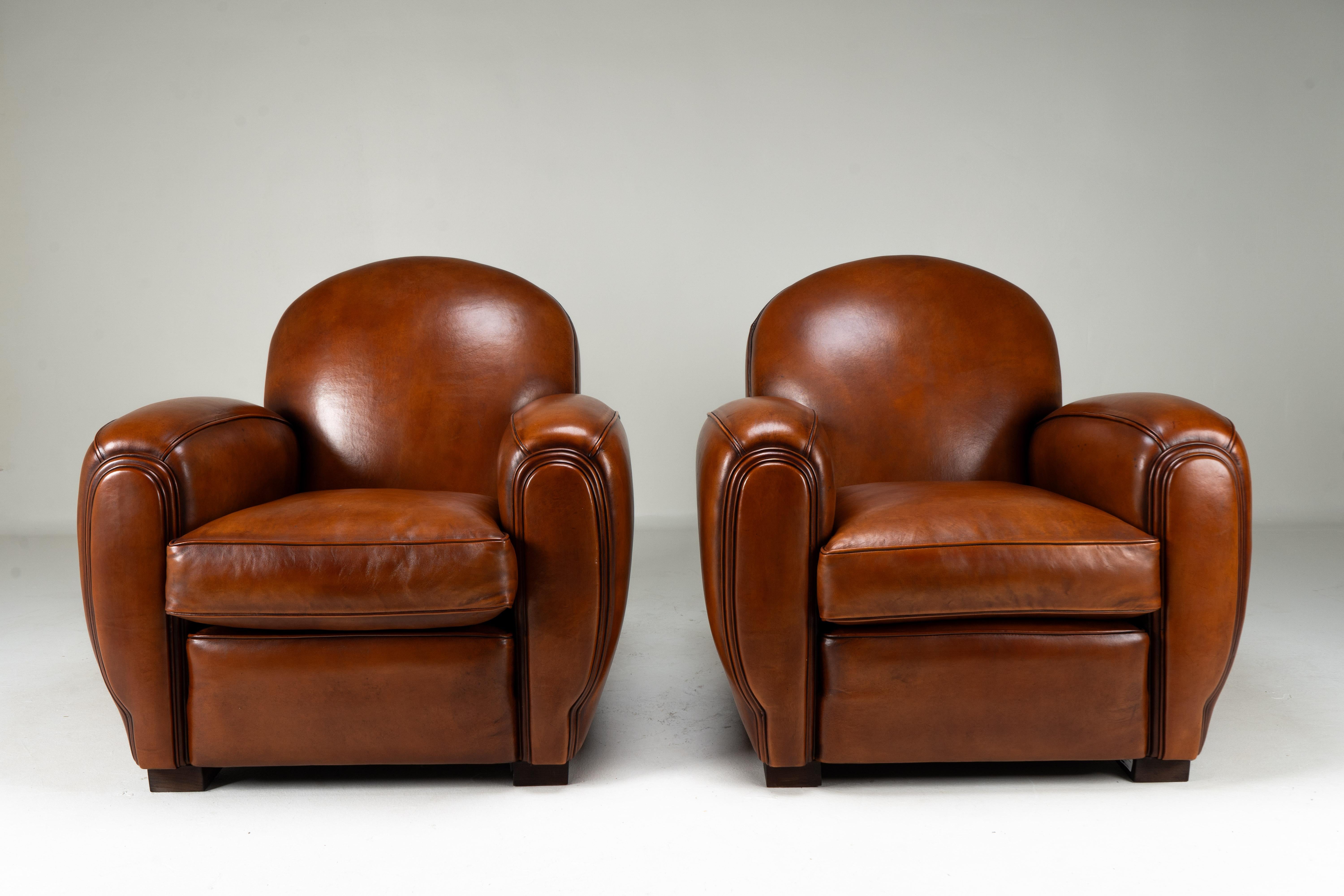 Cette paire de fauteuils club contemporains Art déco français est une trouvaille exceptionnelle. Avec un design datant du mouvement Design/One des années 1920-1940, ces chaises définissent une ère de style parisien. La couleur brun-noisette a une