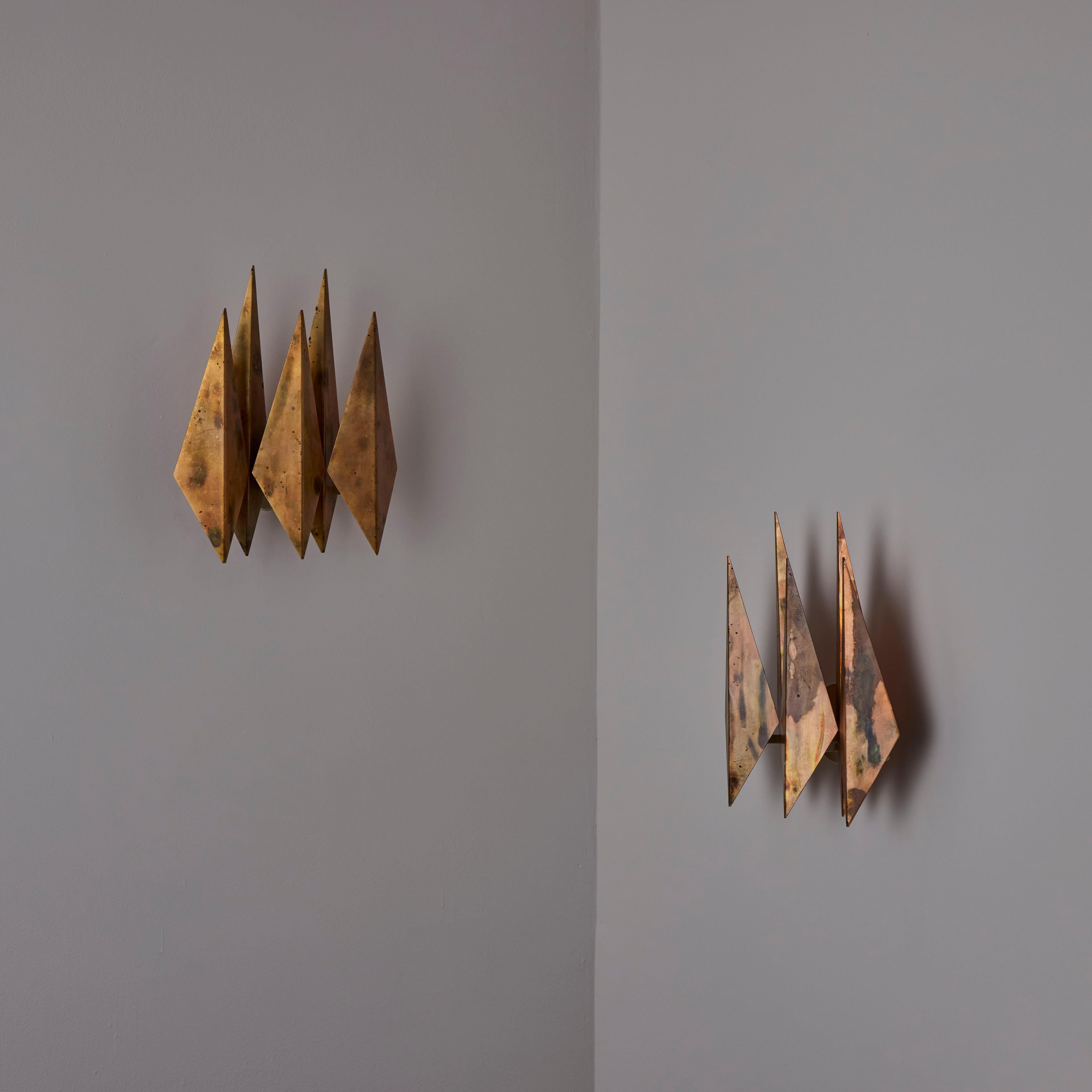 Cette applique murale, conçue par Svend Aage Holm Sørensen au Danemark dans les années 1960, capture l'essence du modernisme scandinave du milieu du siècle avec son design audacieux et sculptural. Fabriqués à partir de plaques de cuivre facettées,