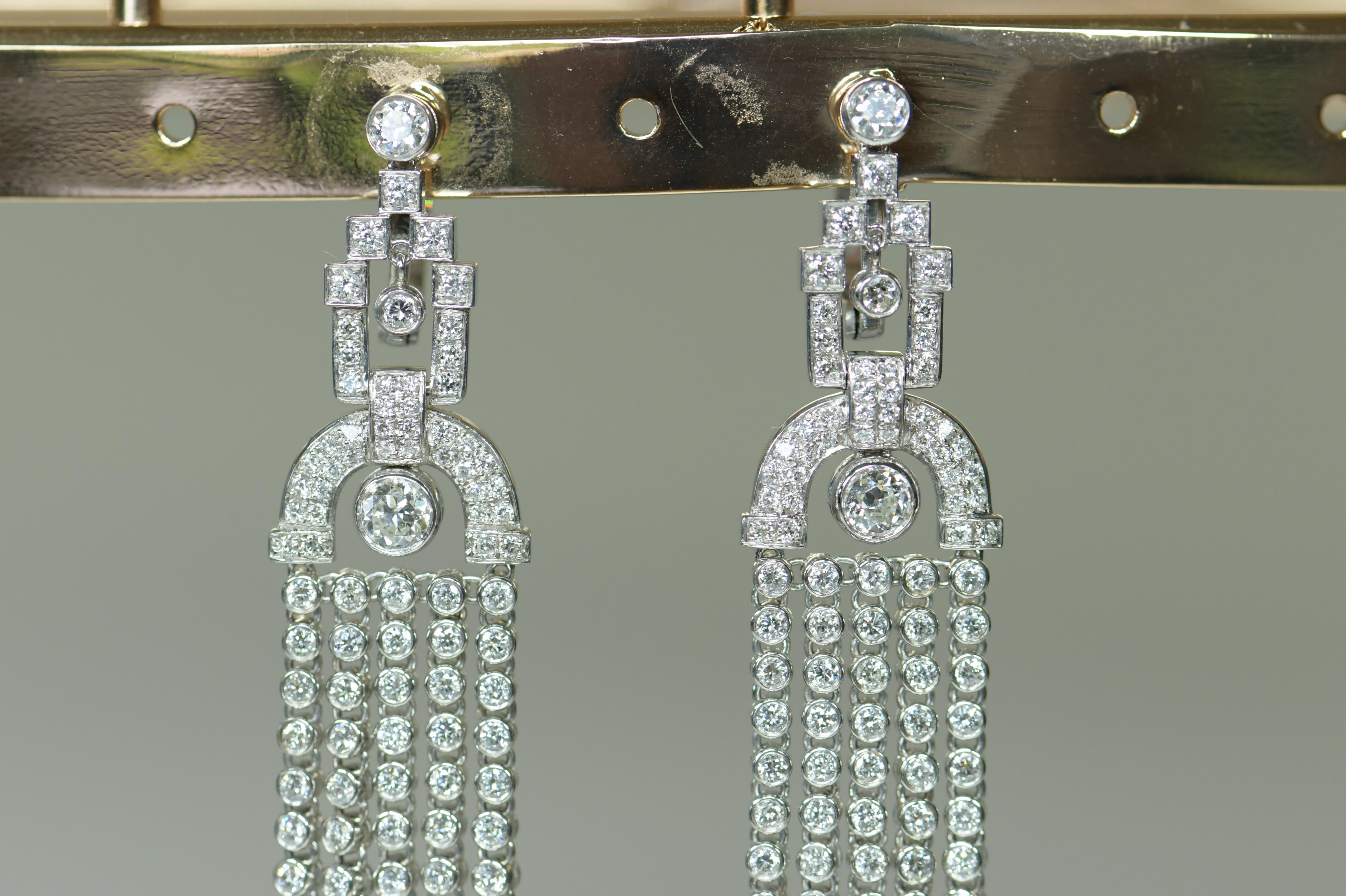 A wonderful pair of gold diamond set earrings which are amazing on the ear as they move and catch the light beautifully. 18K white gold, each formed as a tassel with five articulated drops pendant from a bulbous top and trefoil surmount, set
