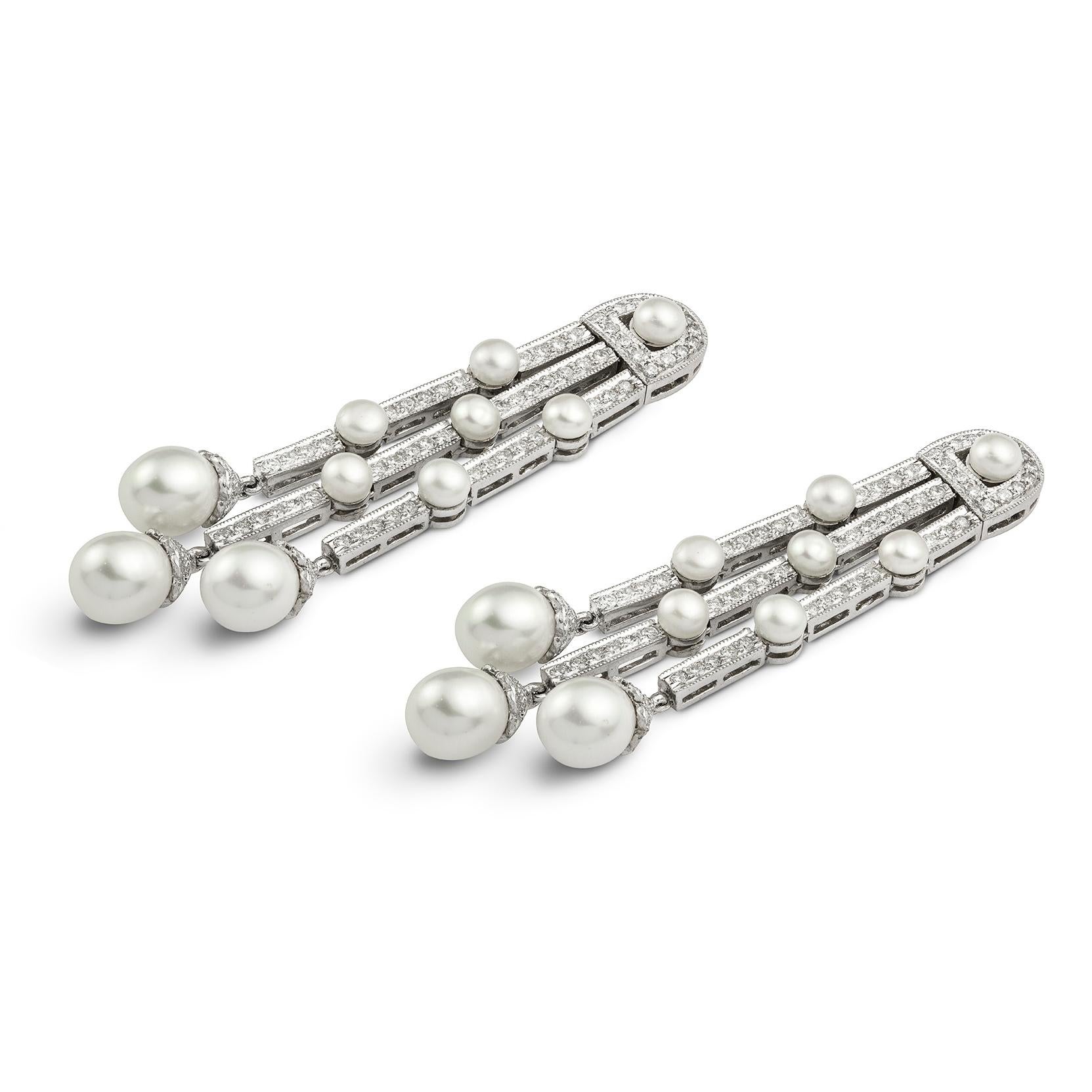 A pair of diamond and cultured pearl drop earrings, each earring of a three graduated pendant drops set with round brilliant-cut diamonds and six cultured bouton pearls each terminated by a cultured pear shape pearl with a diamond-set cap, suspended