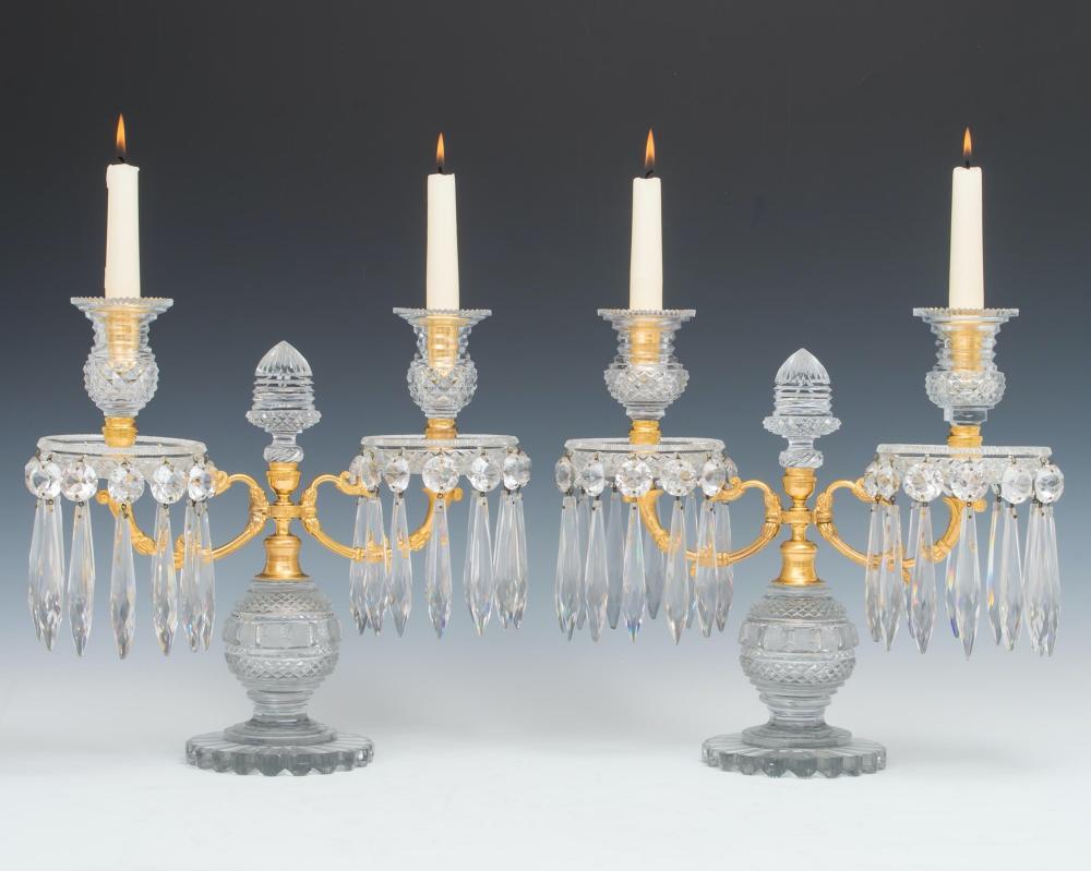 The elaborately cut bases of bulbous form mounted with ormolu serpentine scroll arms supporting diamond cut drip pans and candle nozzles the centre issuing acorn cut glass finials the candelabras hung with double cut spangles and icicles