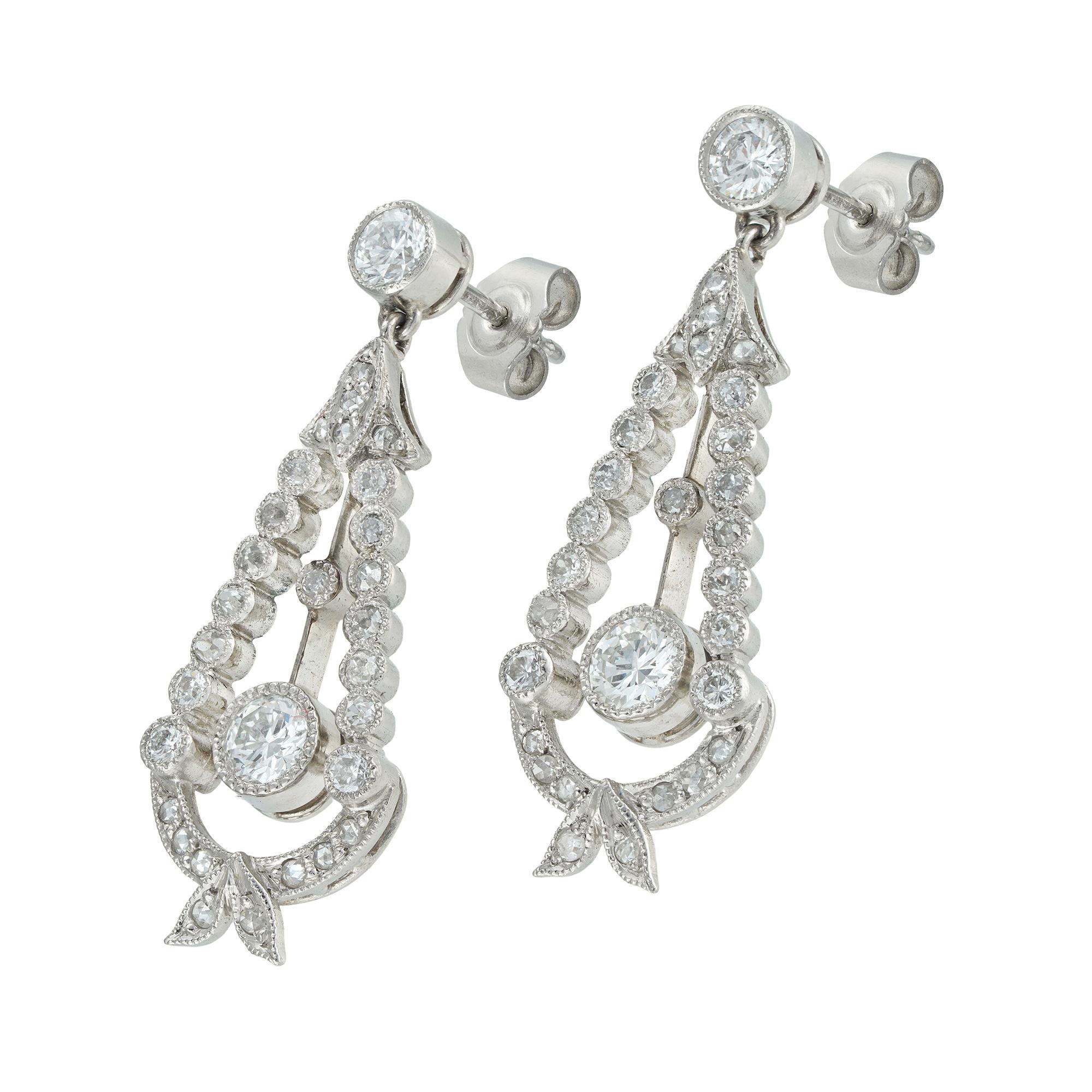 A pair of diamond-set drop earrings, each earring comprising an old brilliant-cut diamond suspended in a frame of old and rose-cut diamonds to form a wreath pattern, surmounted by a single old brilliant-cut diamond, all diamonds weighing
