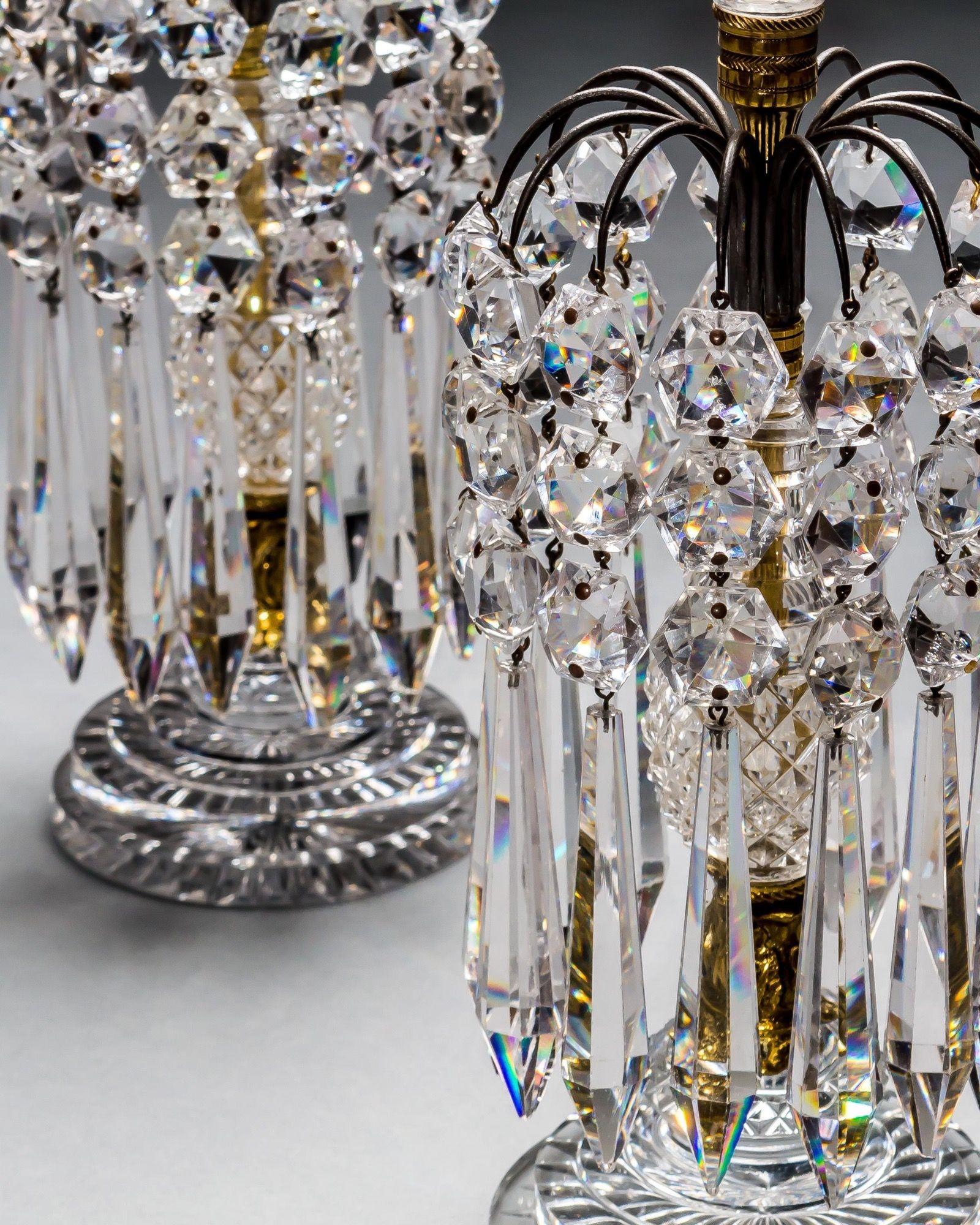 A pair of round, step and diamond cut based candlesticks with gilt mounted centre column and bronze, icicle hung umbrellas.