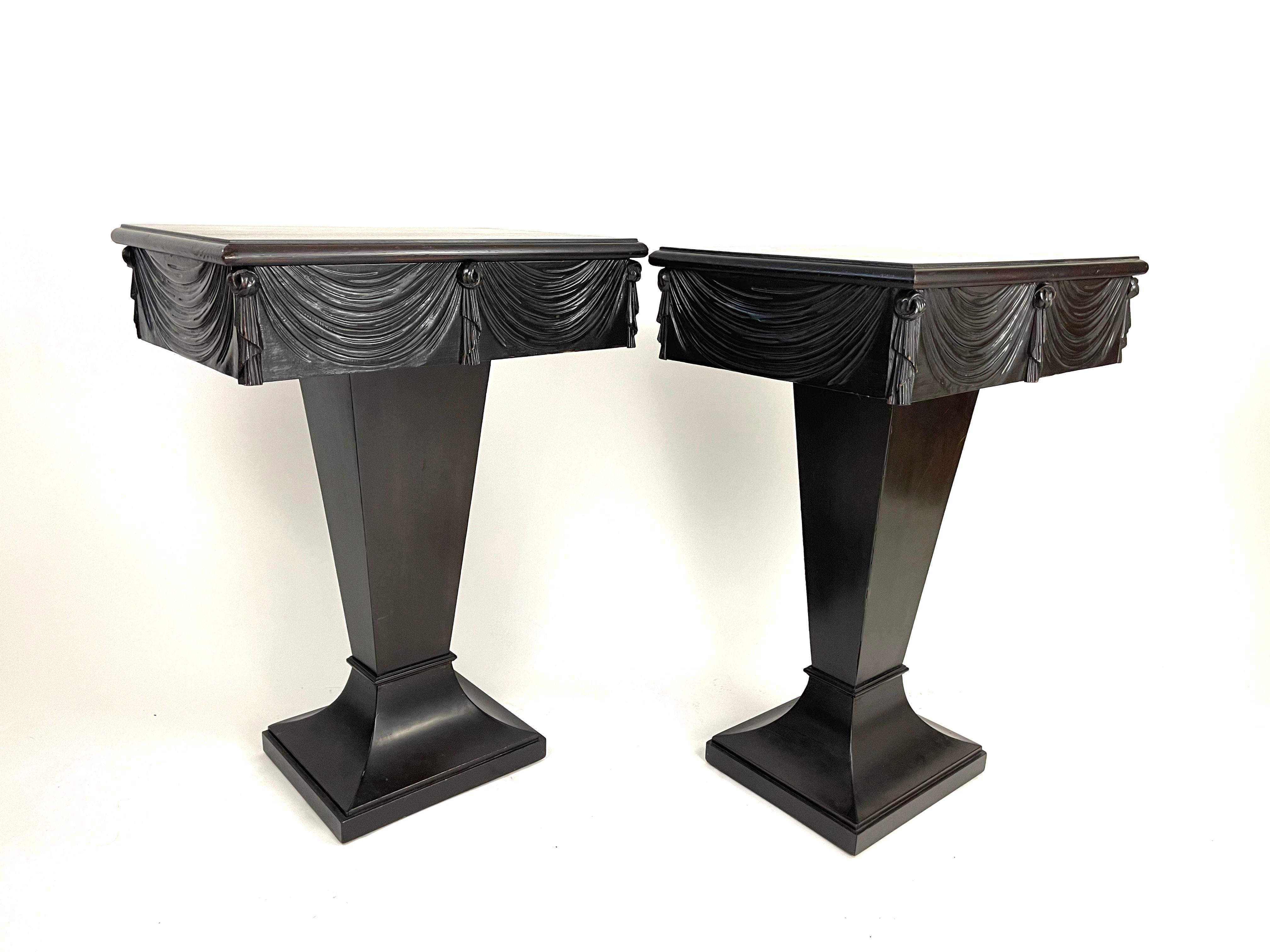 A chic pair of Dorothy Draper Grosfeld House end or night tables, each with rectangular top above a swag-carved apron with tassel decoration and fitted with a single invisible drawer, raised on square tapering supports over a spreading rectangular