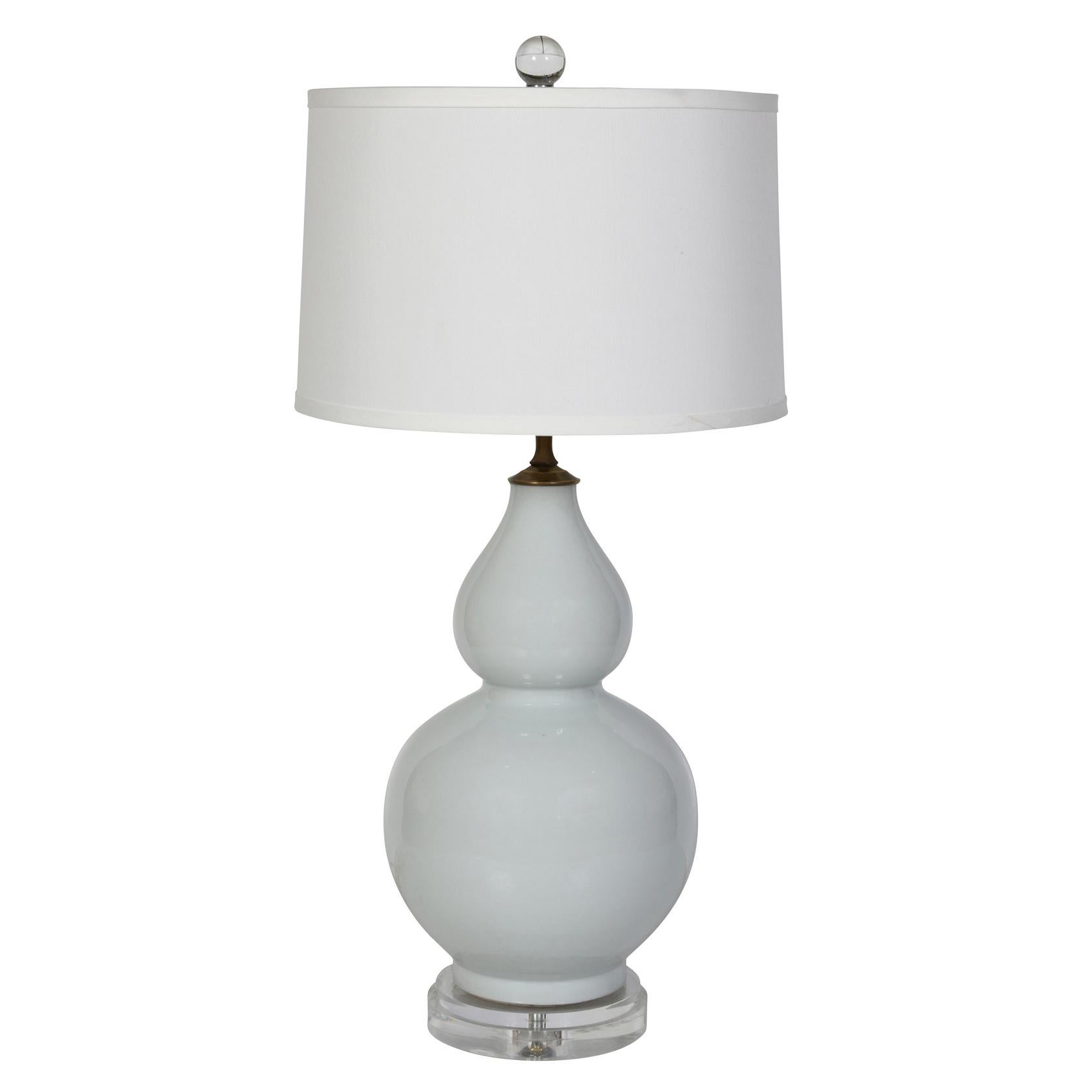 A pair of light gray double gourd  shaped ceramic lamps on a lucite base with a white linen shade.   Simple and elegant, the neutral color of the lamps allow them to go with any color scheme.