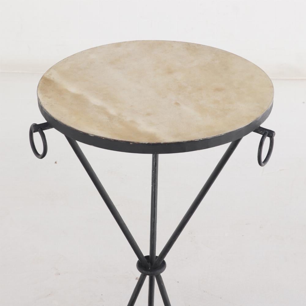 Paire de tables à boissons en fer avec plateaux ronds recouverts de parchemin et tablier décoré d'anneaux, soutenues par une base tripartite en fer.