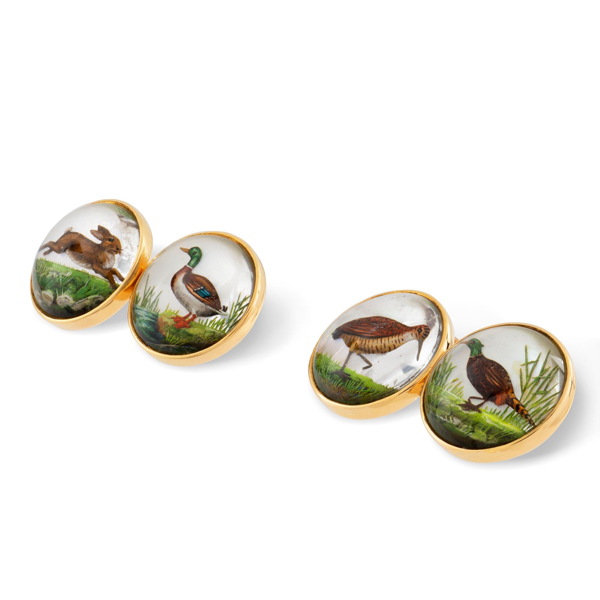 A pair of Dunhill reverse intaglio crystal cufflinks, the cabochon-cut crystal faces each depicting different game animal, measuring approximately 1.4cm in diameter, set on an 18 carat gold rubover mount with gold link fittings, made by Dunhill