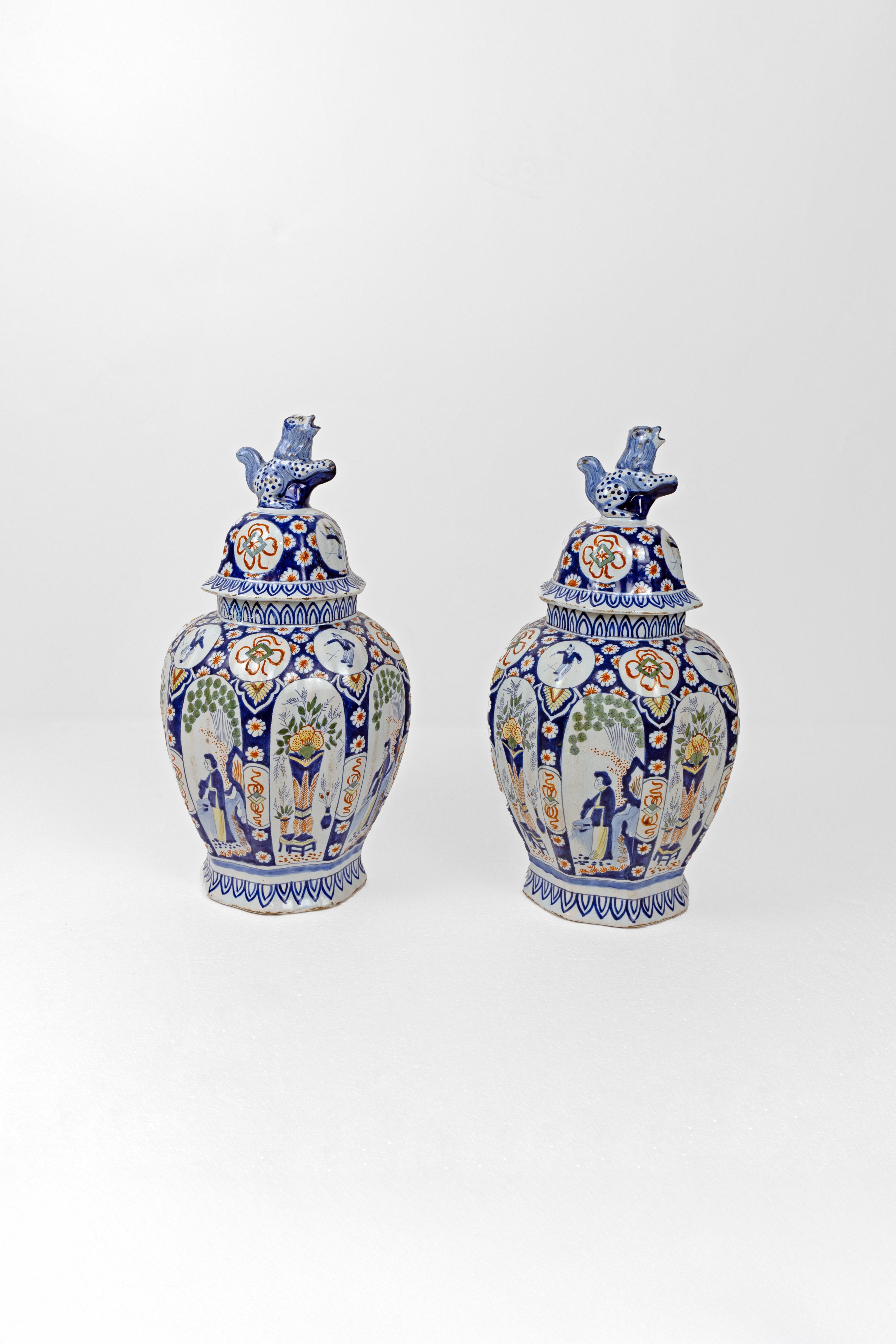 Paire de vases couverts en étain glacé polychrome avec des fleurons en forme de chien de foo, chacun surmonté de fleurons d'animaux fantaisistes bleus et blancs. Le décor peint à la main s'enroule autour d'un cobalt, d'un rouge et d'un vert
