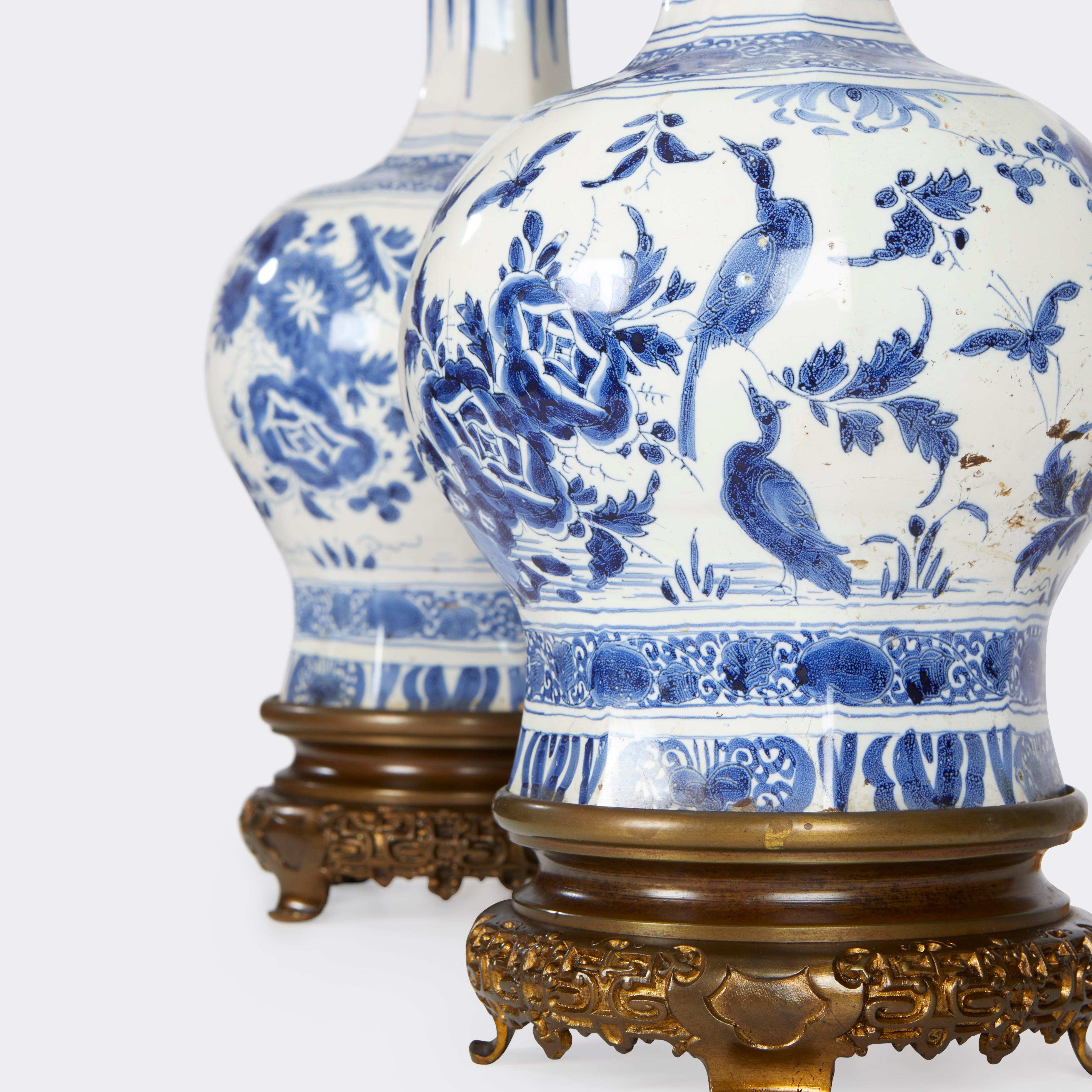 A pair of 19-century delft vases with traditional decoration with blue on white ground mounted with Chinese-inspired bases. Retaining its original oil fitting, now electrified with an adjustable double cluster. 

Dimension: 8'' diameter x vase