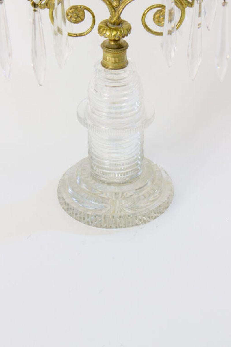 Ein Paar Kandelaber aus geschliffenem Glas und Bronze. Regency-Stil, hergestellt in England, ca. 1815. Schritt schneiden Basis und Kerze Tassen. Bronze Blattstiel und Fuß. Die Kristalle hängen an geschliffenen Glasbögen. Das Glas ist in