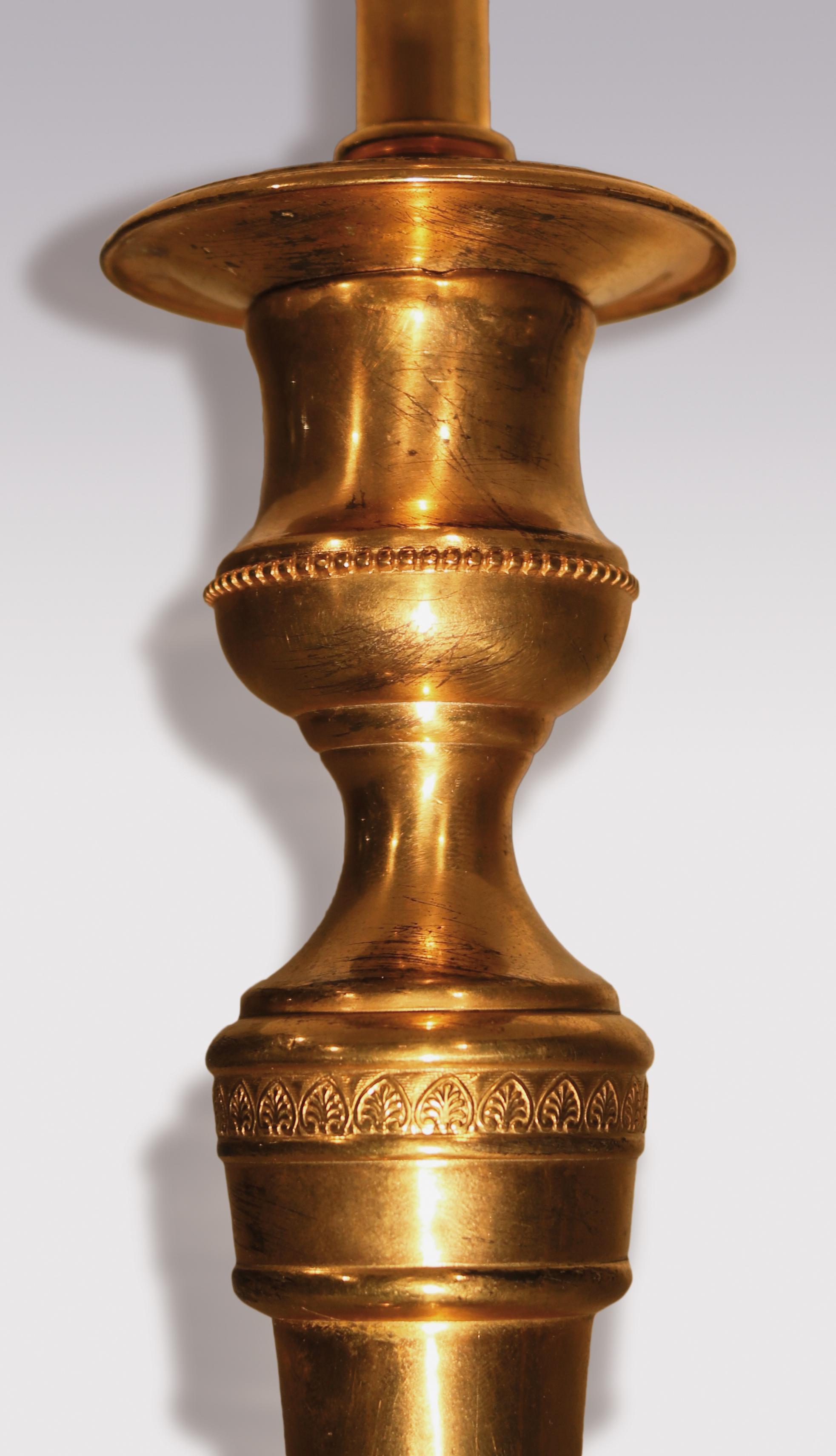 Ein Paar Ormolu-Kerzenleuchter aus dem frühen 19. Jahrhundert mit perlenbesetzten Düsen, die auf sich verjüngenden Stielen mit Löwentatzenfüßen stehen, die auf kreisförmigen Basen enden. Jetzt in Lampen umgewandelt. Höhe des Kerzenhalters 9