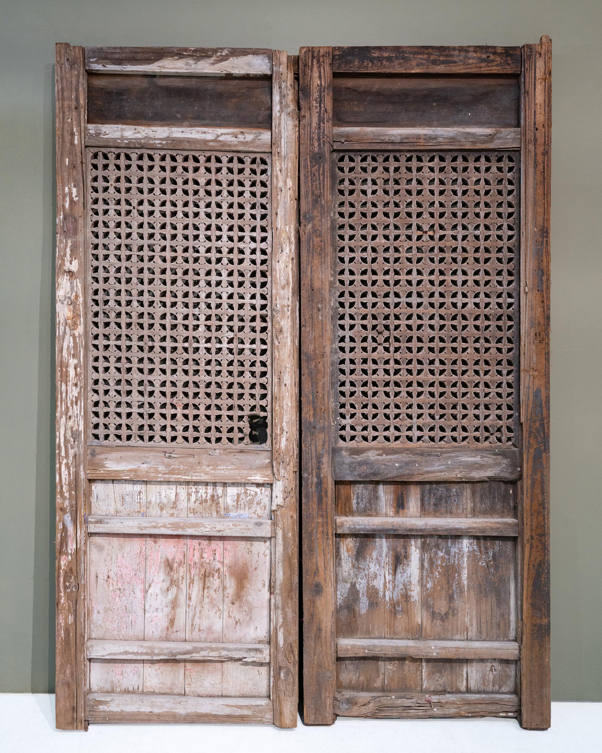 A pair of early 20th century door panels from Fujian province, China. The top panels have beautiful relief carvings of cherry blossoms, Buddha's citron and pumpkins. The floral lattice pattern in the main section is quite unusual for doors from this