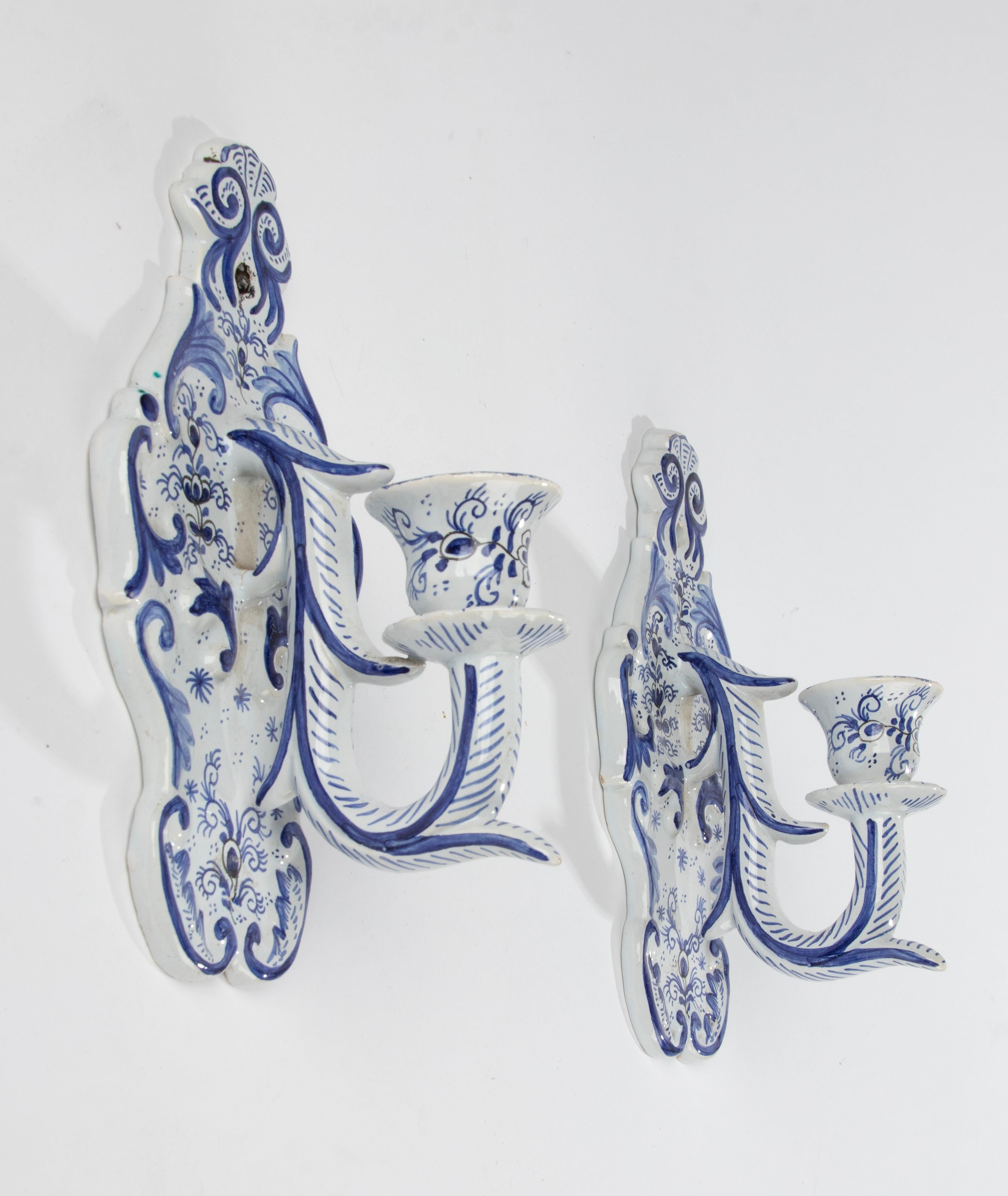 A pair of decorative Delft candlesticks, made of earthenware, hand painted with a blue and white pattern.
The candlesticks can also be made electrically and have small holes for wire to pass through. But they are also charming as wall holders for